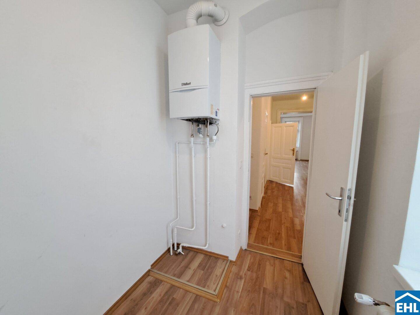 Kleiner Hauswirtschaftsraum mit einer Wandheizungsanlage und Laminatboden.