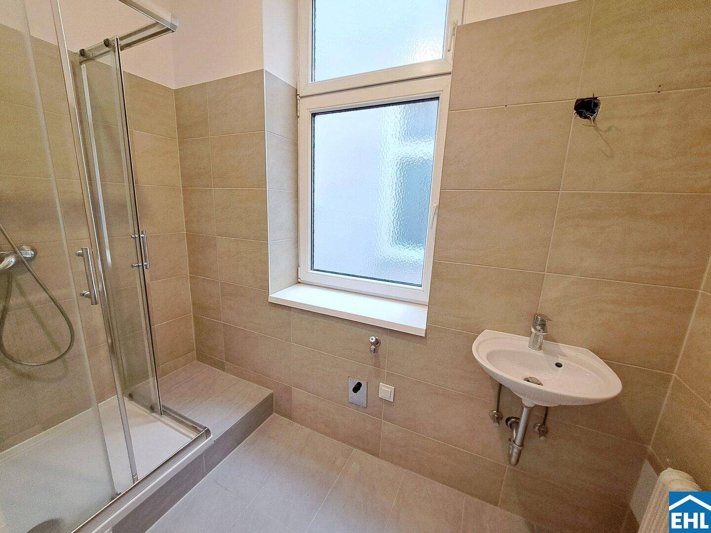 Funktionales Badezimmer mit Duschkabine, Einzelwaschbecken und einem Fenster für natürliche Belüftung.