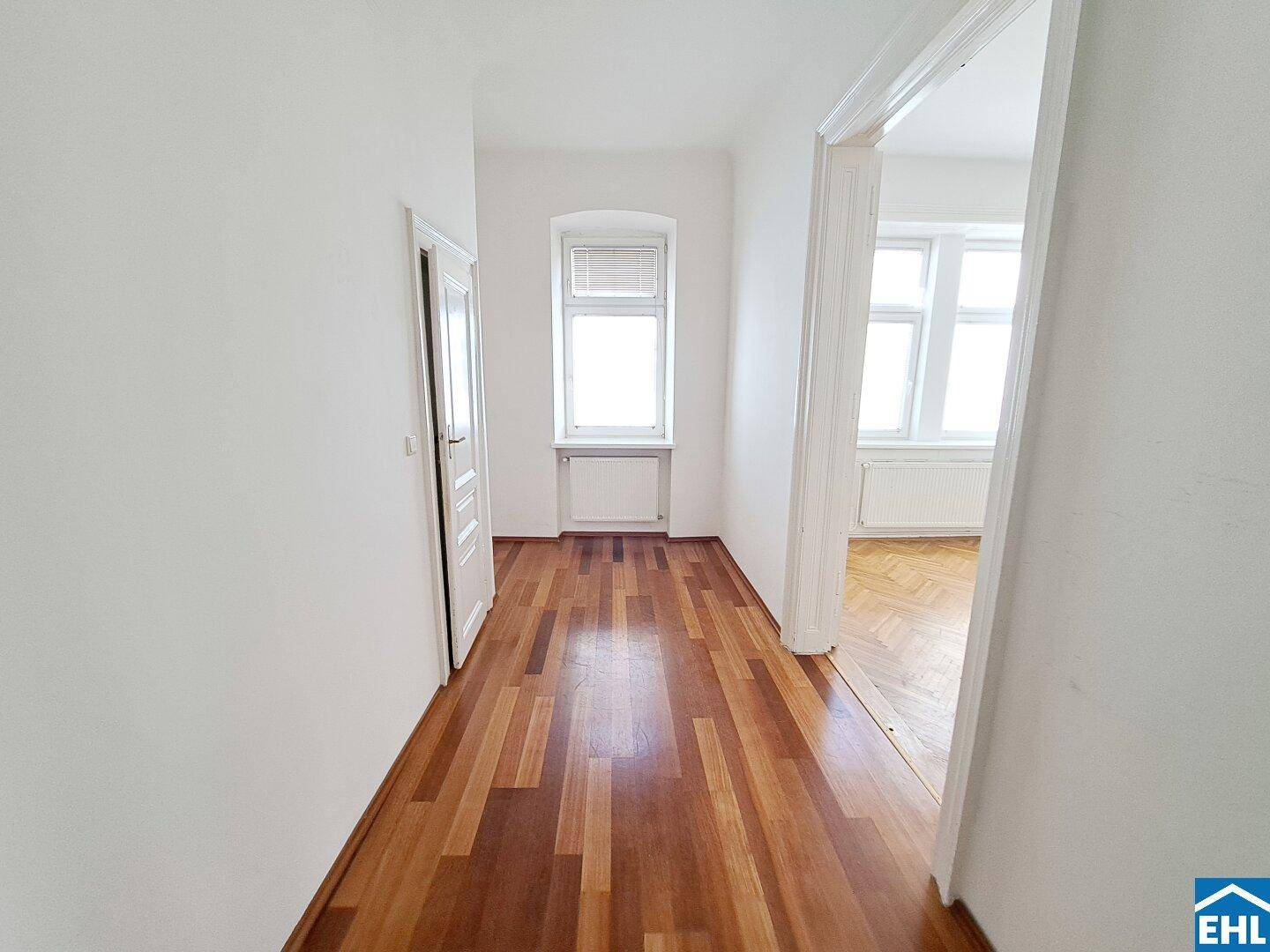 Heller Flur mit Holzparkett und Blick in angrenzende Räume, der vielseitig nutzbar ist.