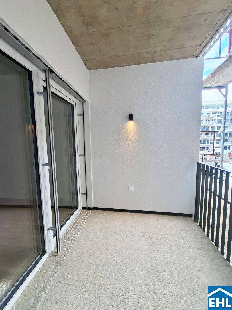 Geräumiger Balkon mit Betonboden und Blick auf die Baustelle, ideal für Entspannung im Freien.