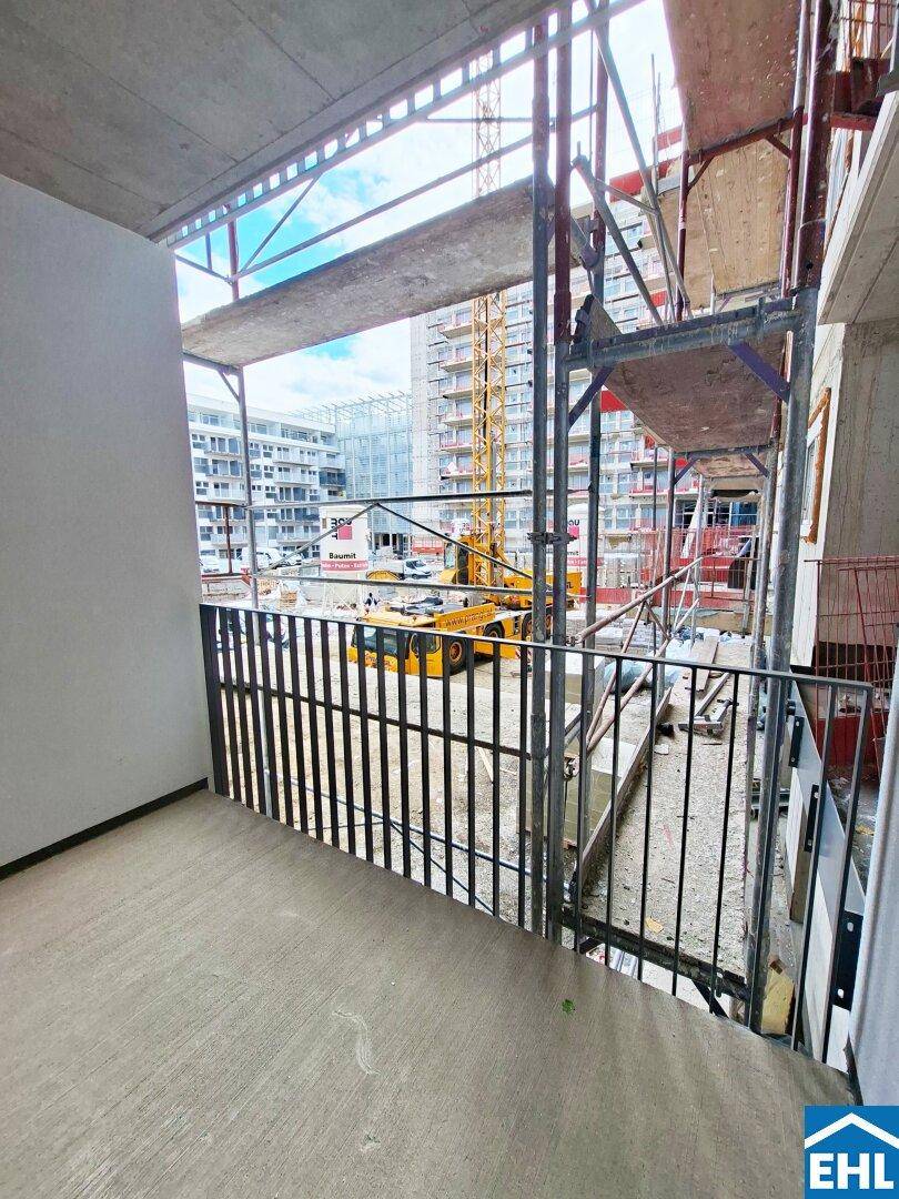 Balkon mit Metallgeländer und weitem Blick auf die umliegende Baustelle und Gebäude.