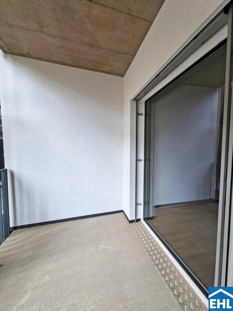 Balkon mit Schiebetür und Betonboden, bietet einen privaten Außenbereich mit Blick auf die Umgebung.