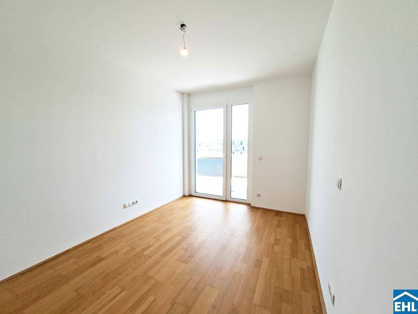 Helles Zimmer mit Parkettboden und großer Balkontür, ideal als Schlaf- oder Wohnzimmer.