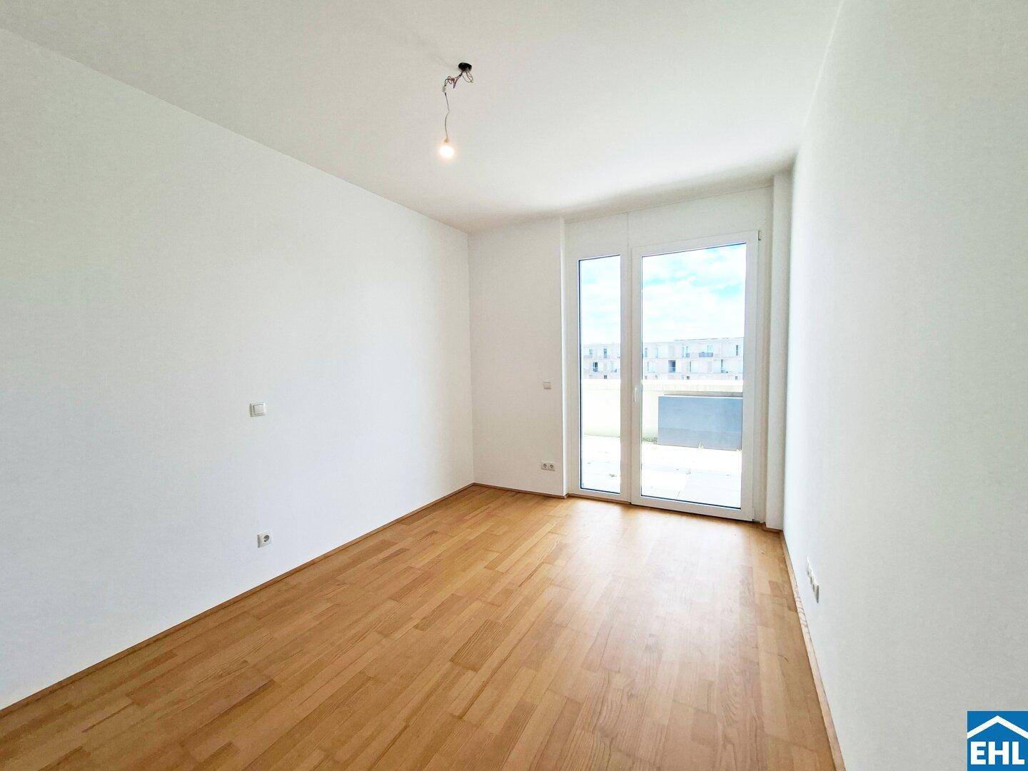 Geräumiges, helles Zimmer mit Parkettboden und direktem Zugang zu einem Außenbereich.