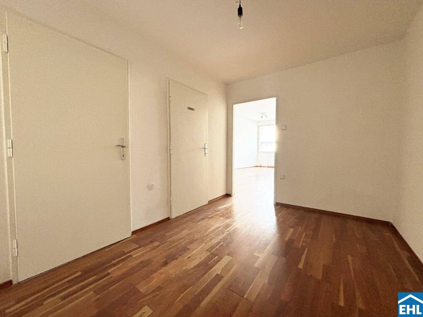 Heller Flur mit Holzboden und mehreren Türen, der zu weiteren Räumen führt.