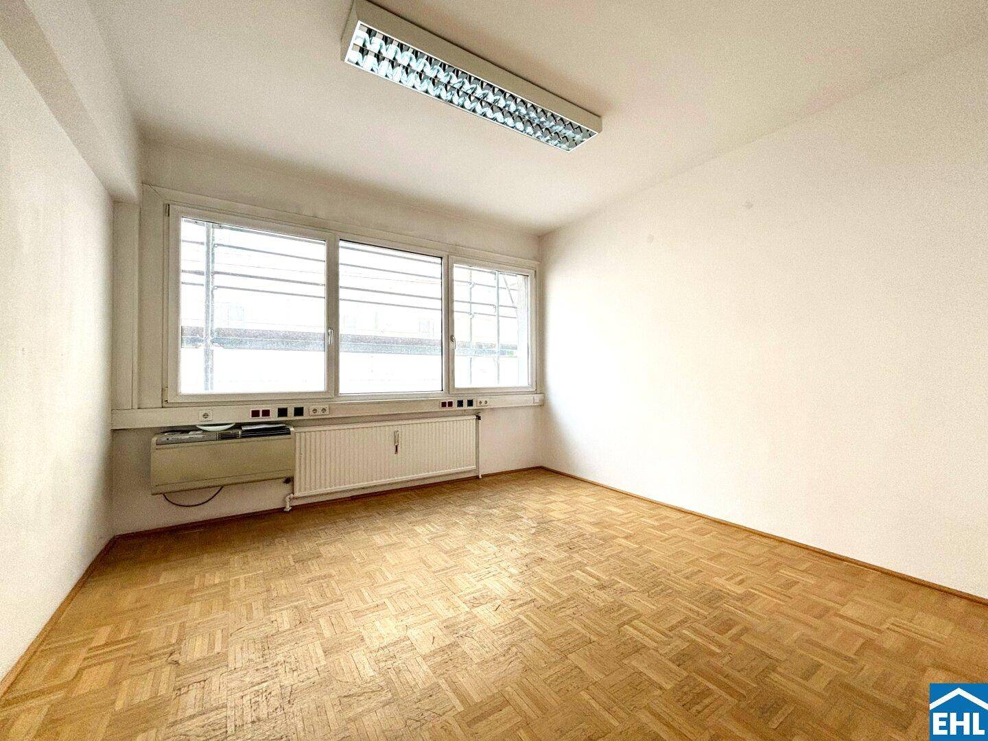 Helles Büro mit Parkettboden und großen Fenstern, ideal für konzentriertes Arbeiten.