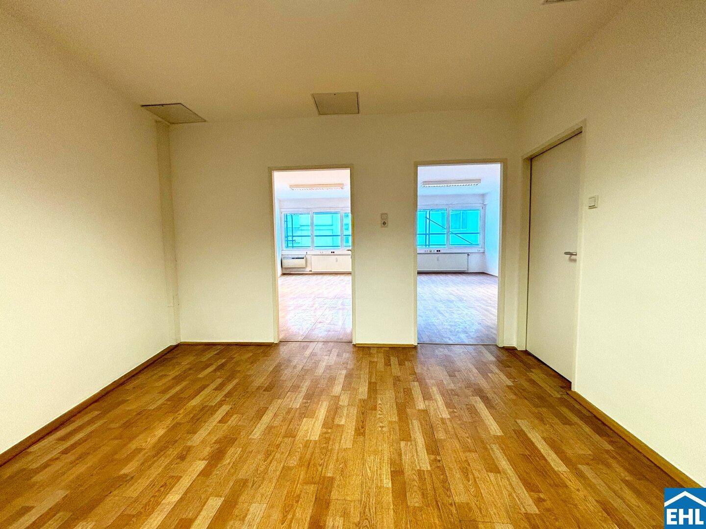 Unmöblierter Raum mit Holzboden und mehreren Türen, der Flexibilität bietet.