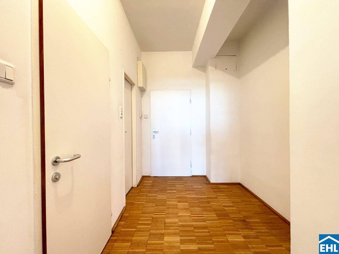 Schlichter Flur mit Parkettboden und mehreren Türen, verbindet die verschiedenen Bereiche der Wohnung.
