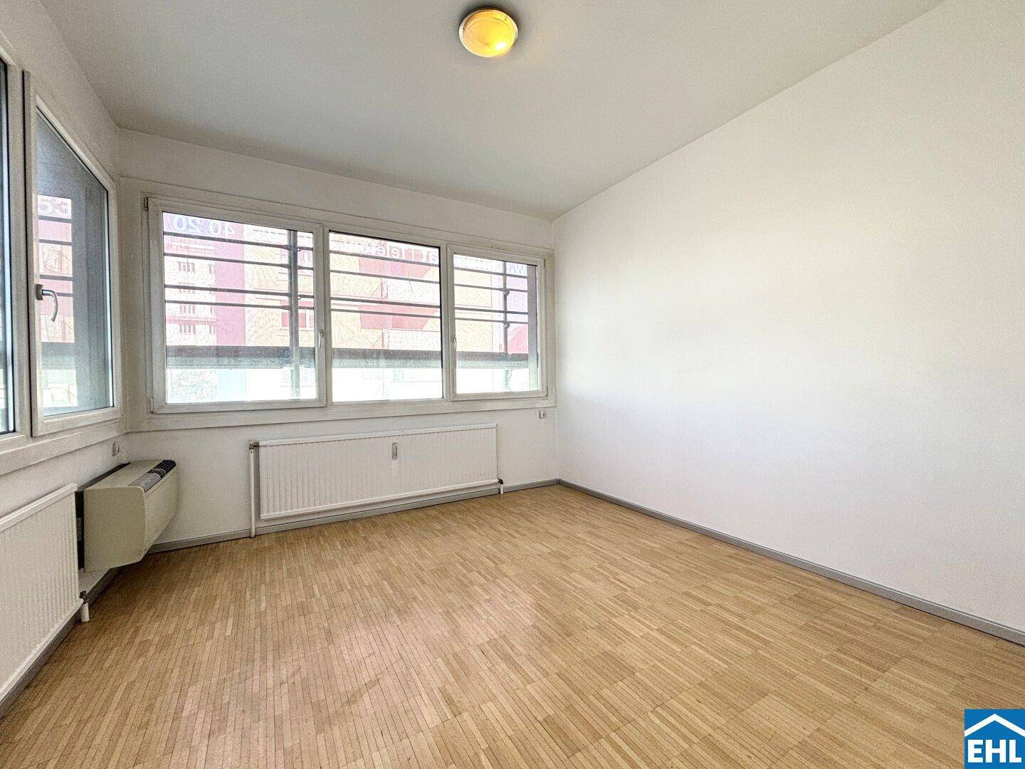 Heller Raum mit großen Fenstern und Parkettboden, bietet viel Tageslicht und eine angenehme Atmosphäre.