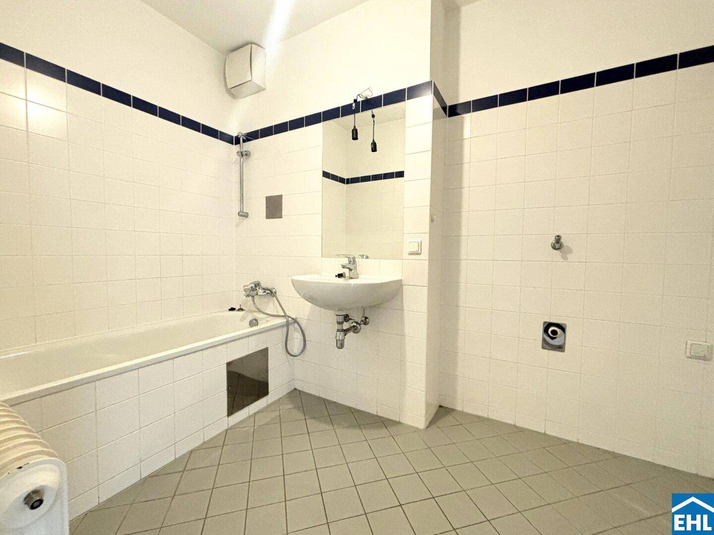 Badezimmer mit weiß gefliesten Wänden, Badewanne und Waschbecken, in funktionalem Zustand.