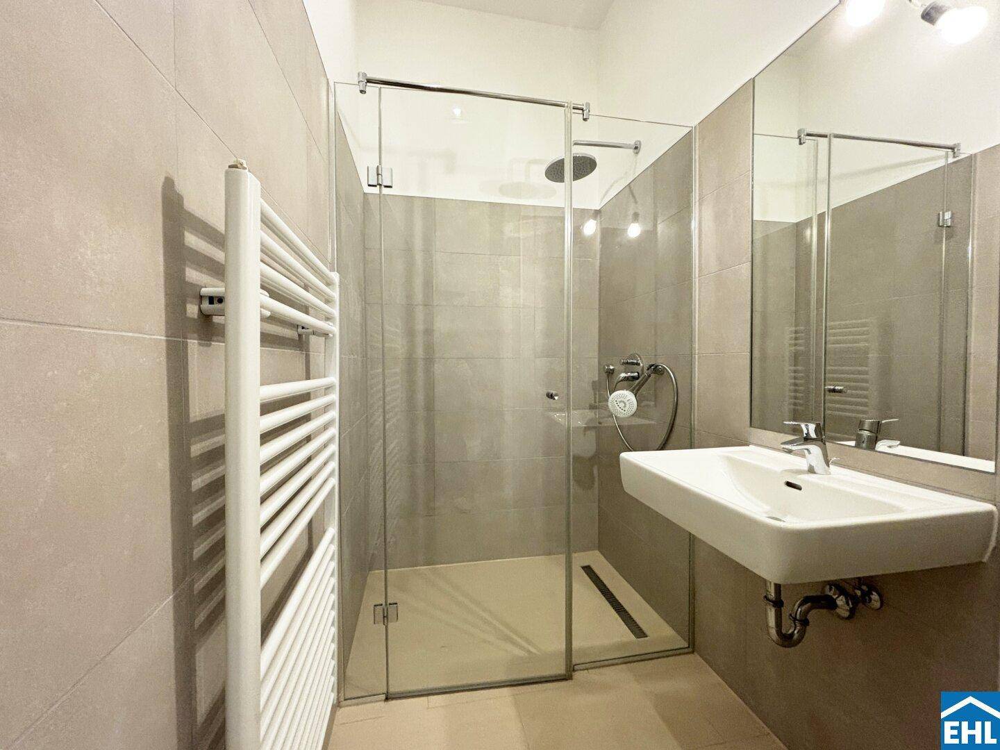 Modernes Badezimmer mit begehbarer Dusche, großformatigen Fliesen und beheiztem Handtuchhalter.