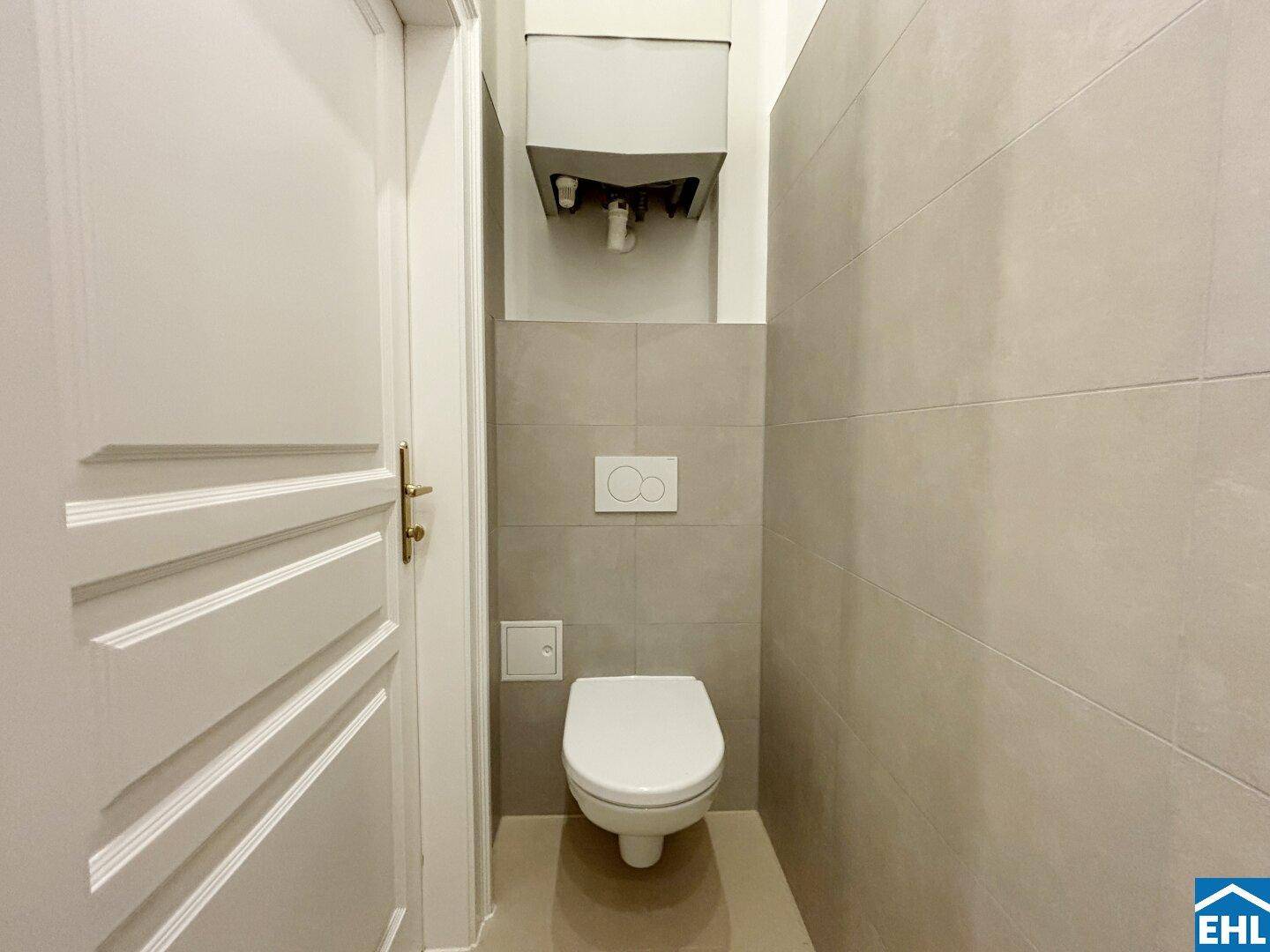 Separates WC mit Wand-WC und hellen Fliesen, funktional und platzsparend gestaltet.