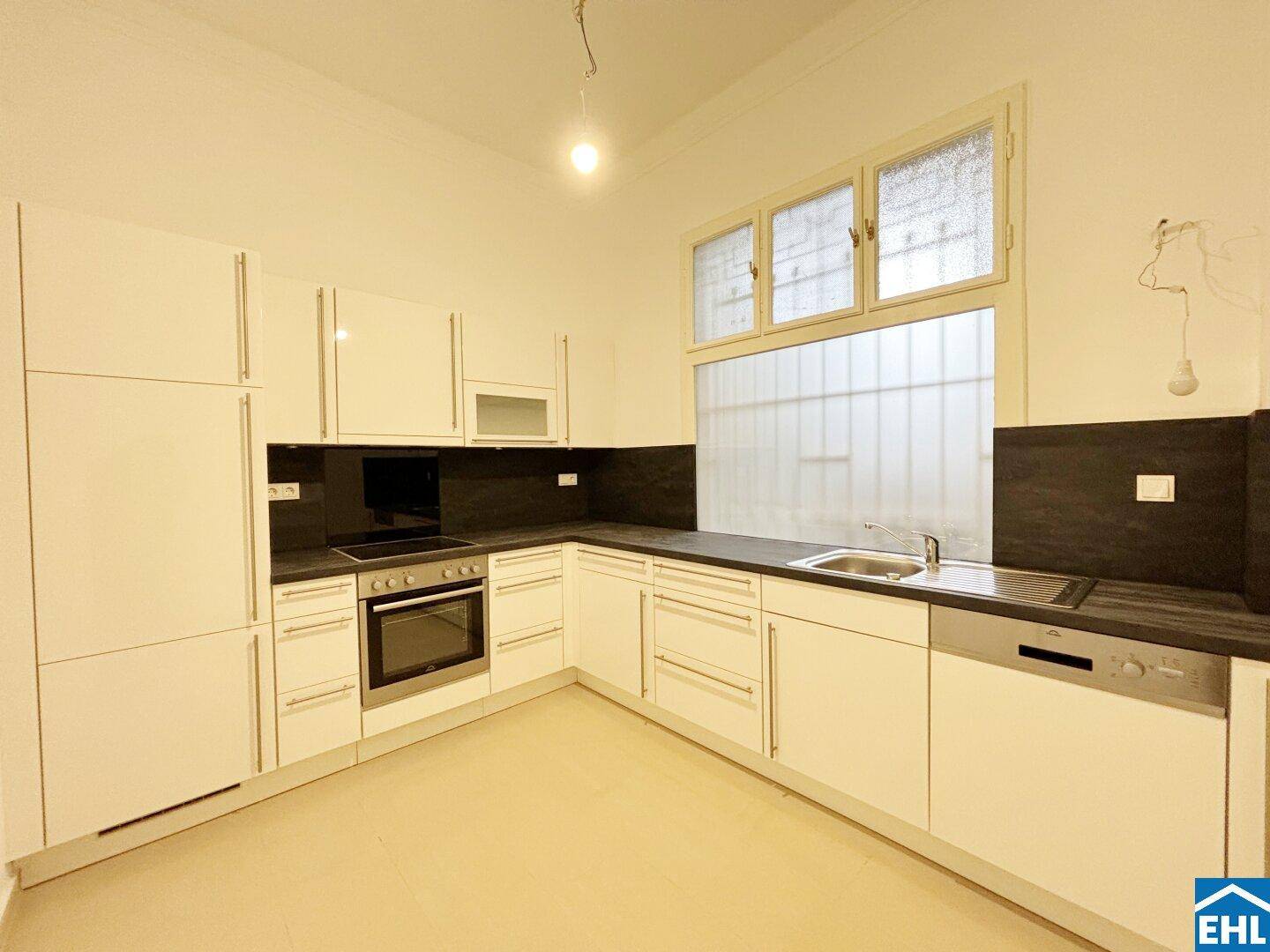 Moderne Einbauküche mit weißen Hochglanzfronten, integrierten Geräten und Spülmaschine.