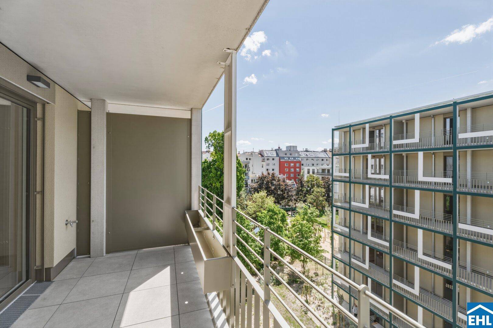 Geräumiger Balkon mit Fliesenboden und weitem Blick auf die Stadt und grüne Bereiche.