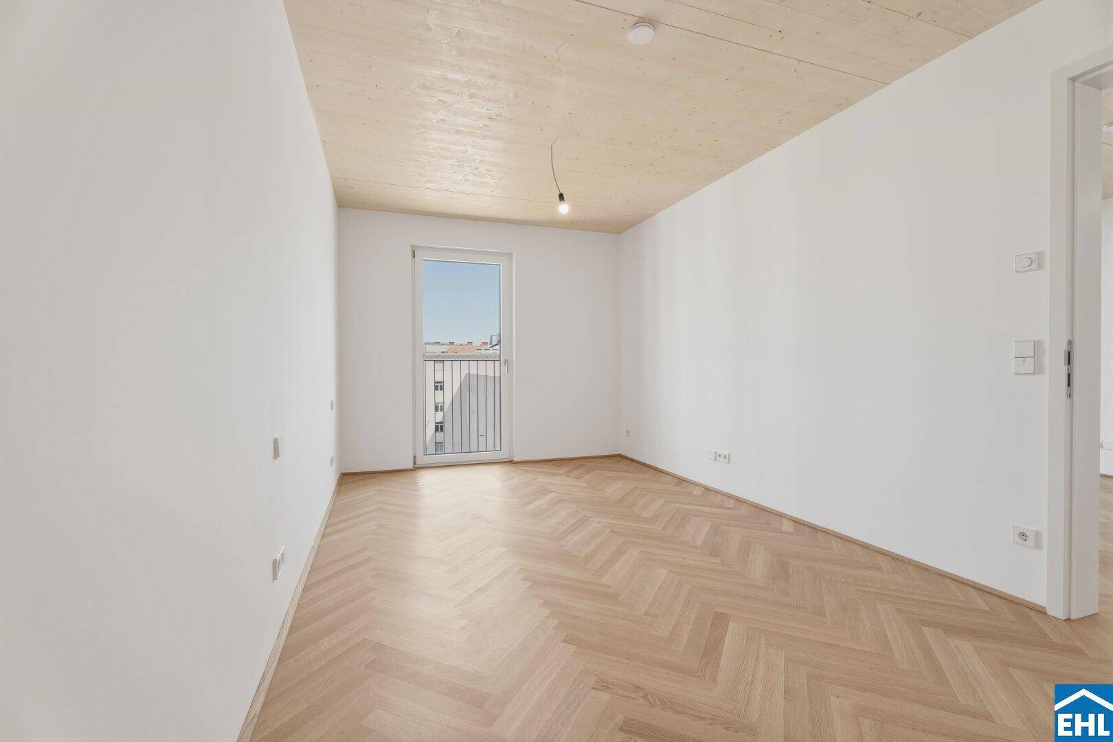 Helles Schlafzimmer mit Parkettboden und Zugang zu einem französischen Balkon.