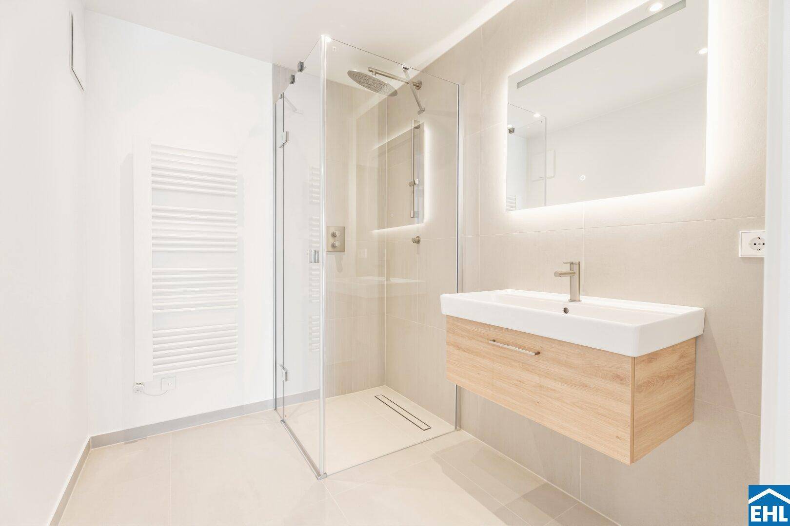 Modernes Badezimmer mit begehbarer Dusche, Waschtisch und beleuchtetem Spiegelschrank.