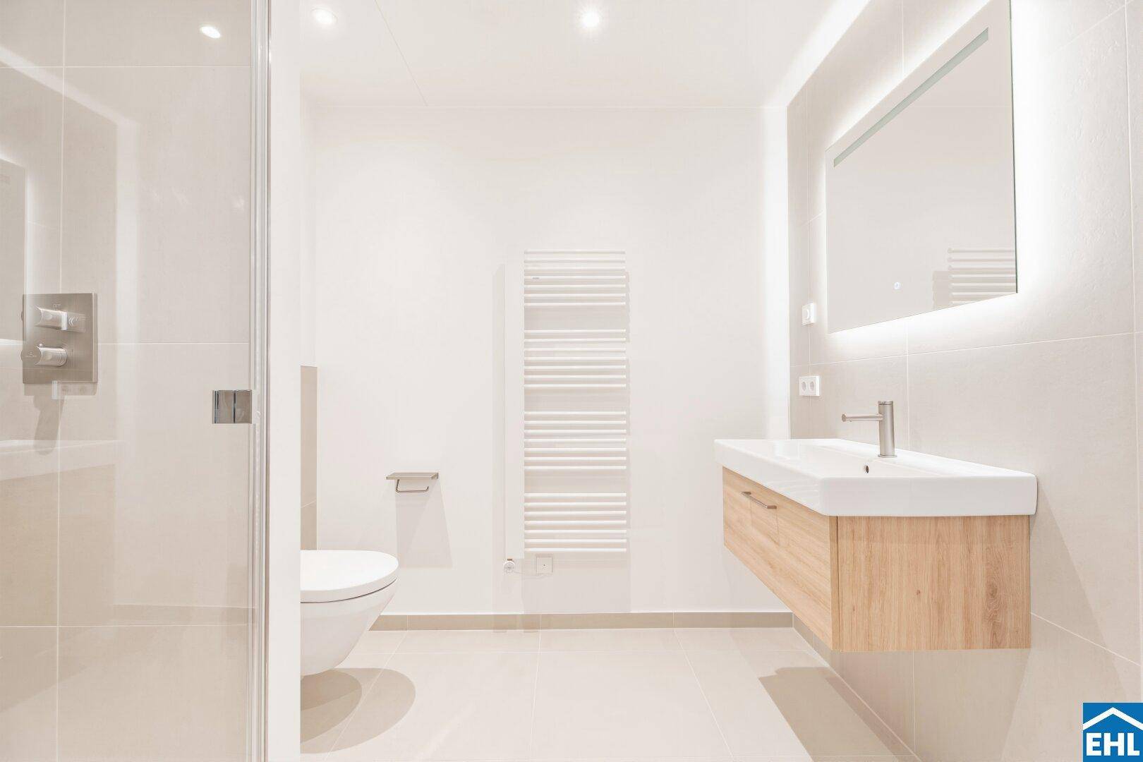 Modernes Badezimmer mit begehbarer Dusche, Wand-WC und beleuchtetem Spiegel.