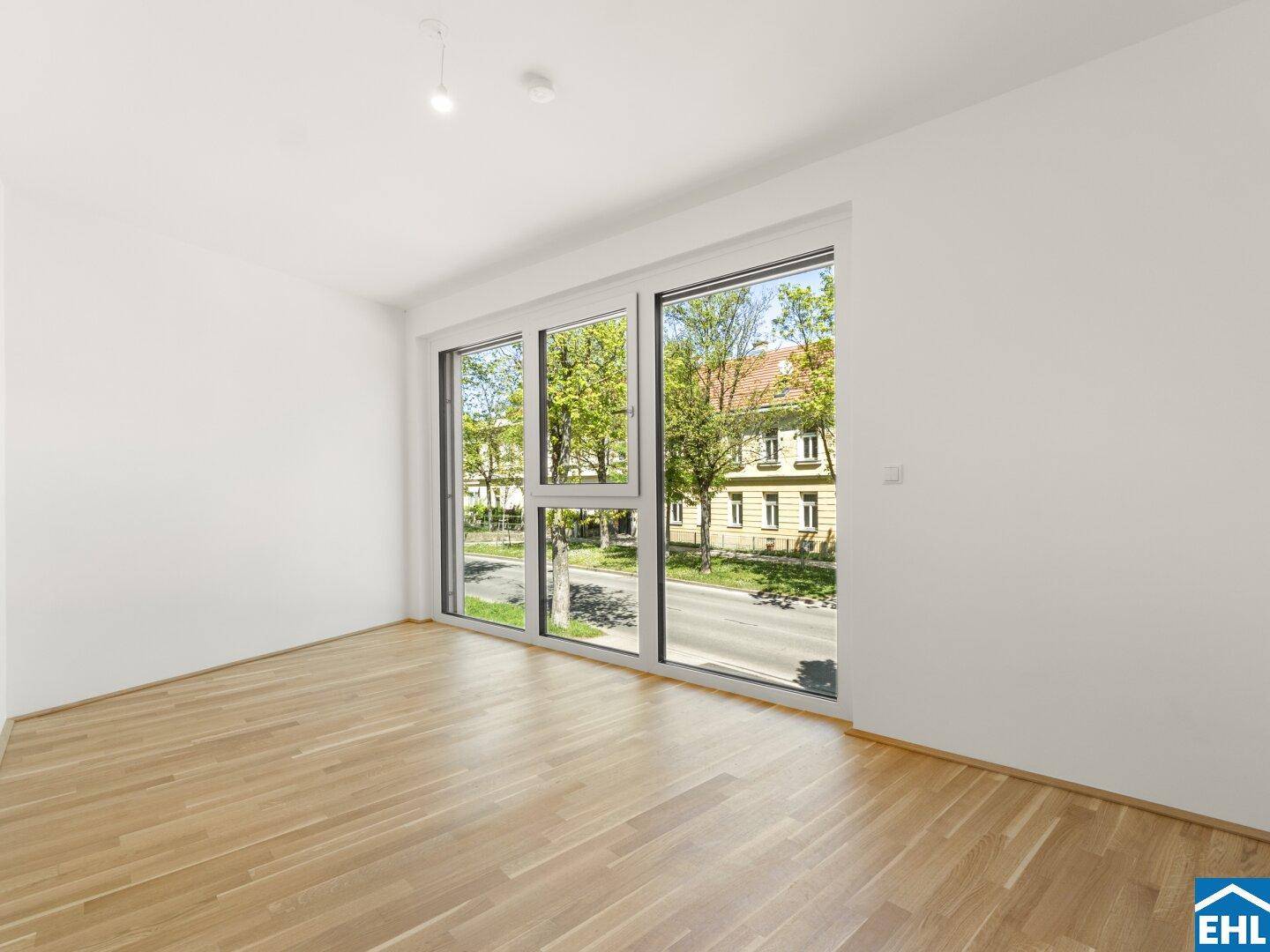 Geräumiges Zimmer mit Eichenparkett und großen Fenstern, die viel Tageslicht hereinlassen und einen Stadtblick bieten.