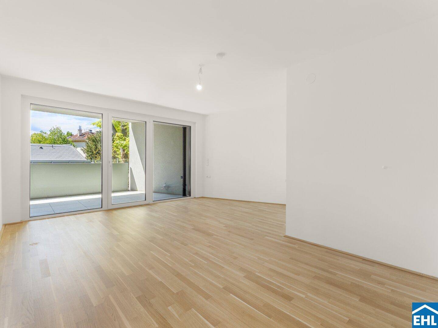 Heller Wohnbereich mit Eichenparkett und direktem Zugang zu einem sonnigen Balkon oder einer Terrasse.