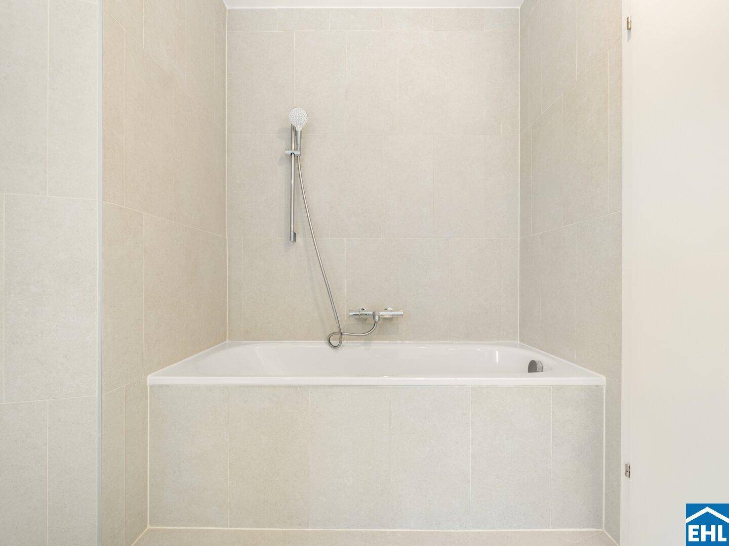 Modernes Badezimmer mit heller Fliesenverkleidung und einer integrierten Badewanne mit Duschfunktion.