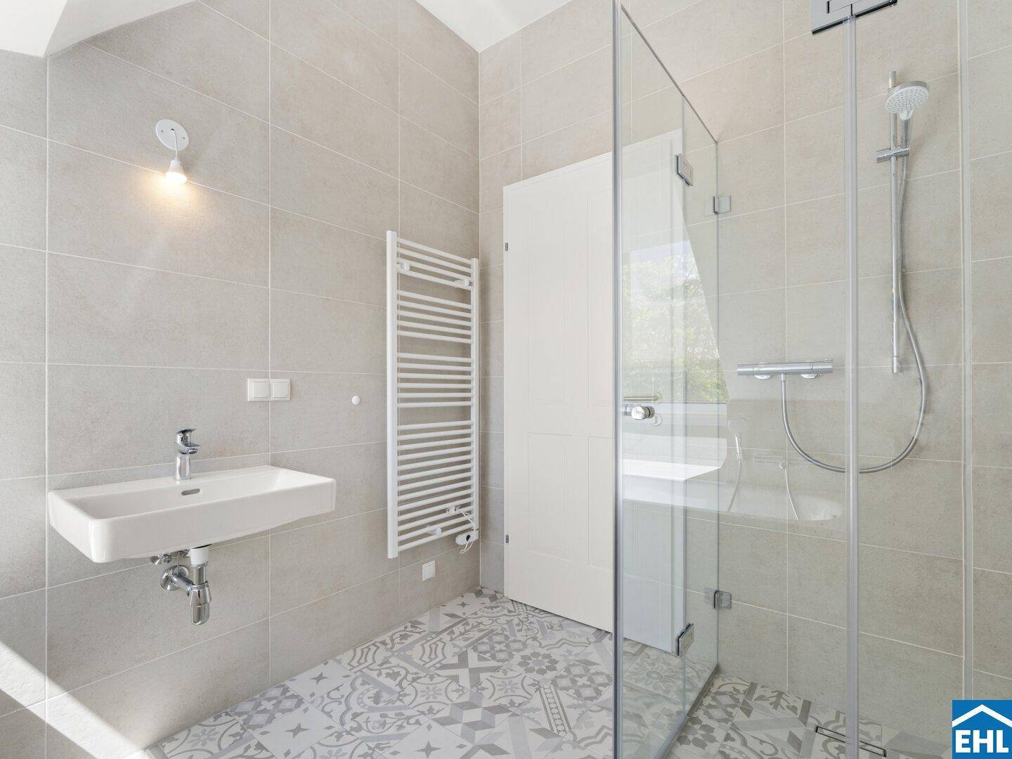 Modernes Badezimmer mit ebenerdiger Dusche, Waschbecken und beheiztem Handtuchhalter.