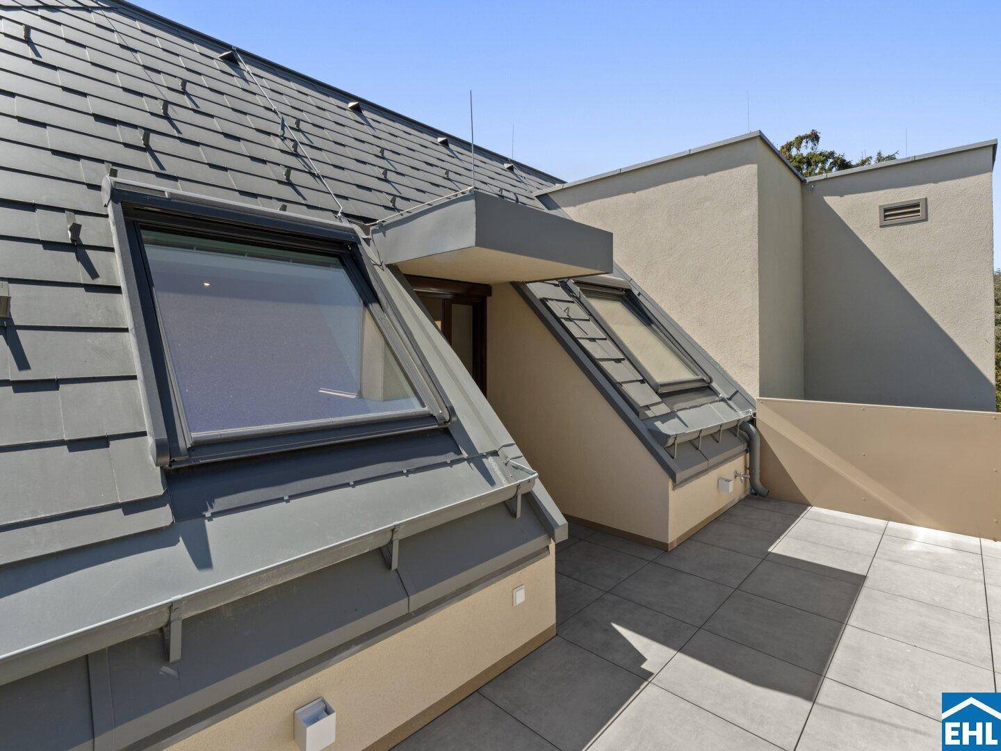 Geräumige Dachterrasse mit Fliesenboden und Blick auf die Umgebung.