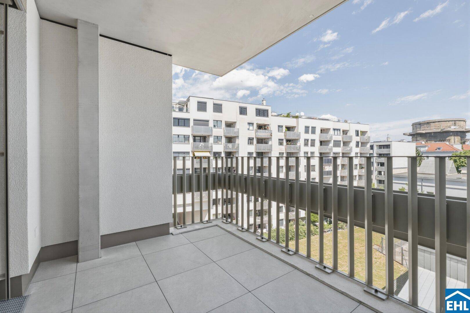 Geräumiger Balkon mit Fliesenboden und Blick auf die umliegenden Gebäude.