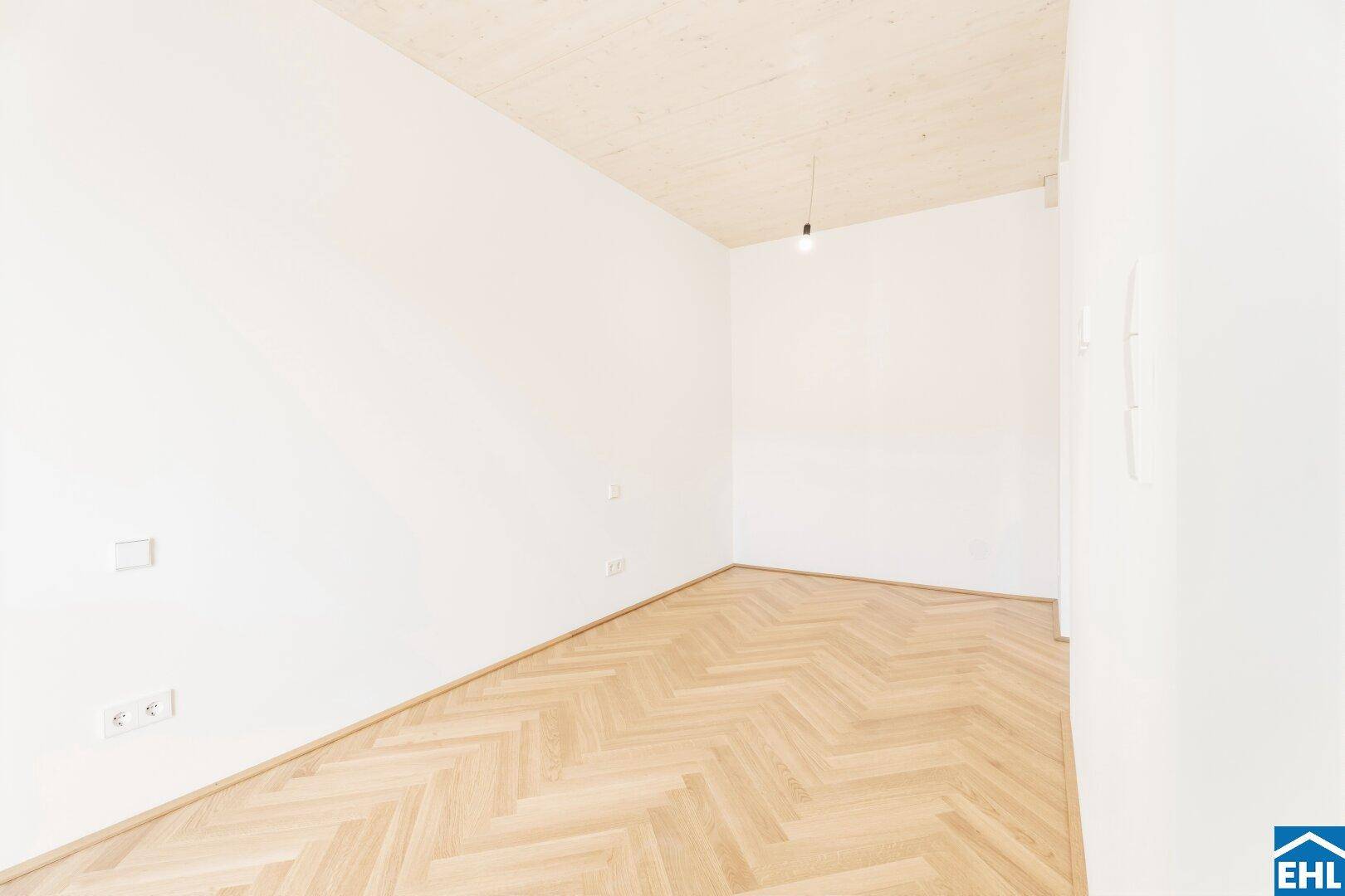 Sauberer, unmöblierter Raum mit neuem Fischgrätparkett und schlichter, moderner Ästhetik.