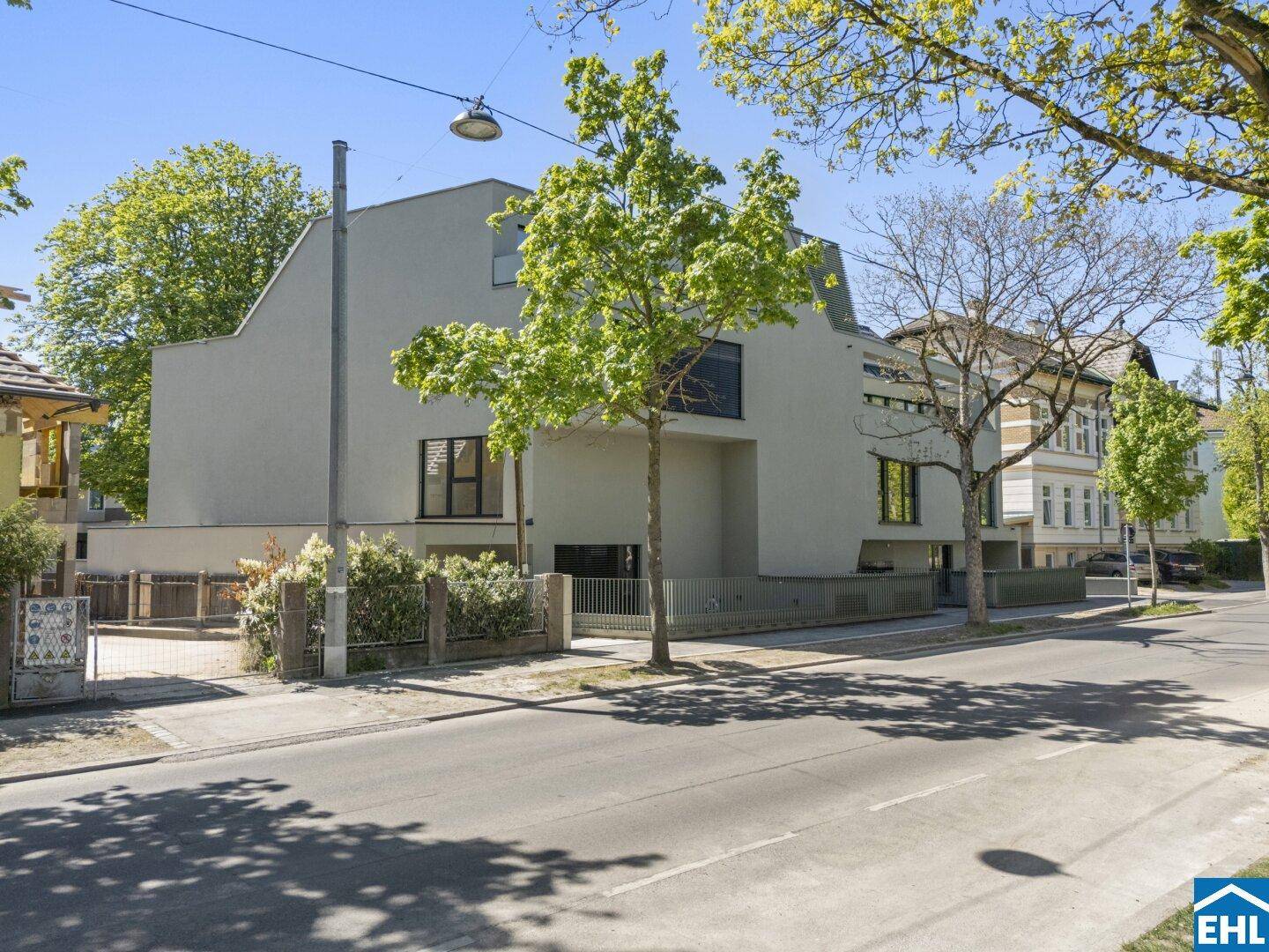 Moderne Architektur des Gebäudes von der Straße aus gesehen, umgeben von Bäumen.