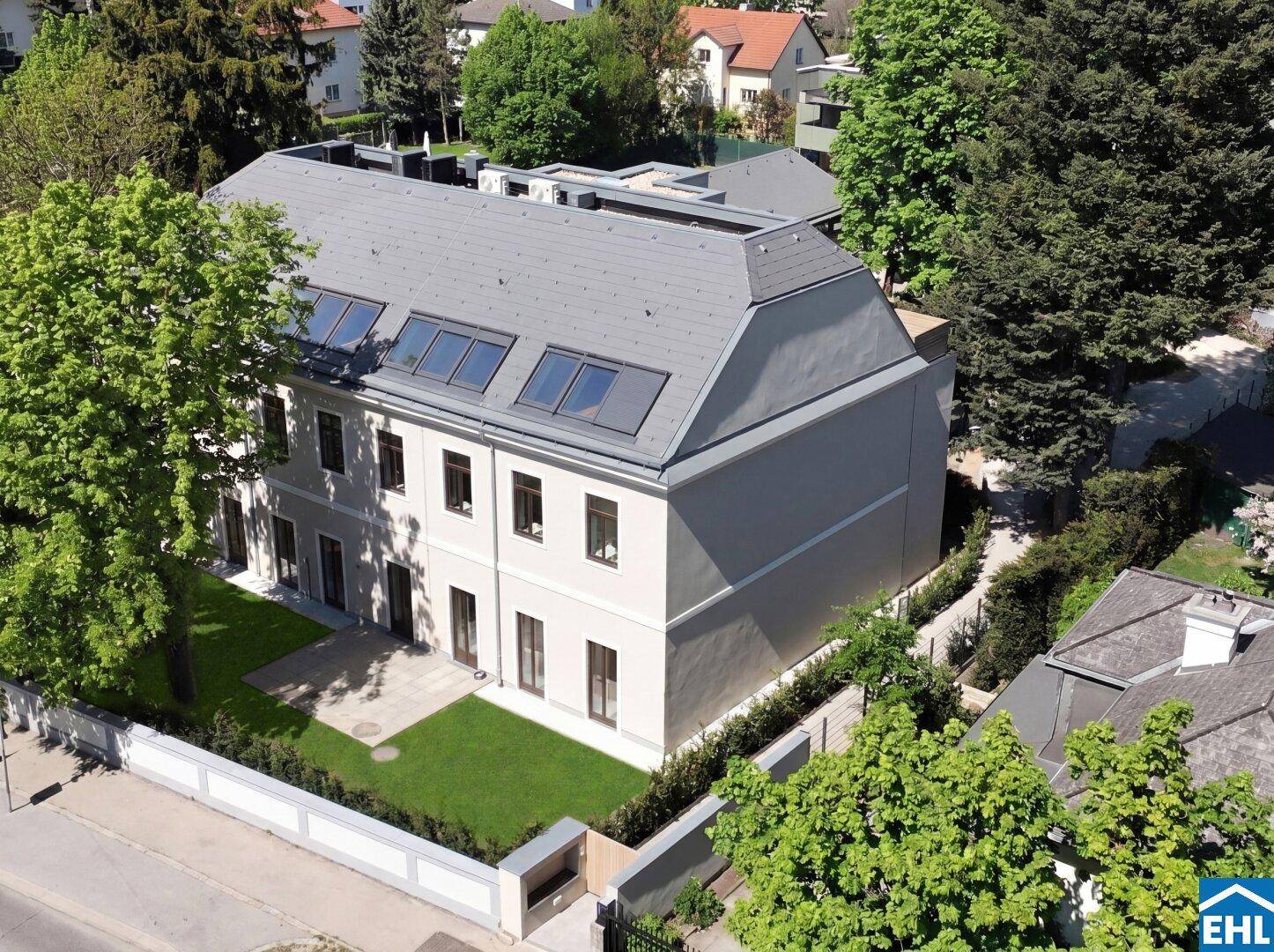 Luftaufnahme des modernen Gebäudes mit Mansarddach und gepflegtem Gartenbereich.
