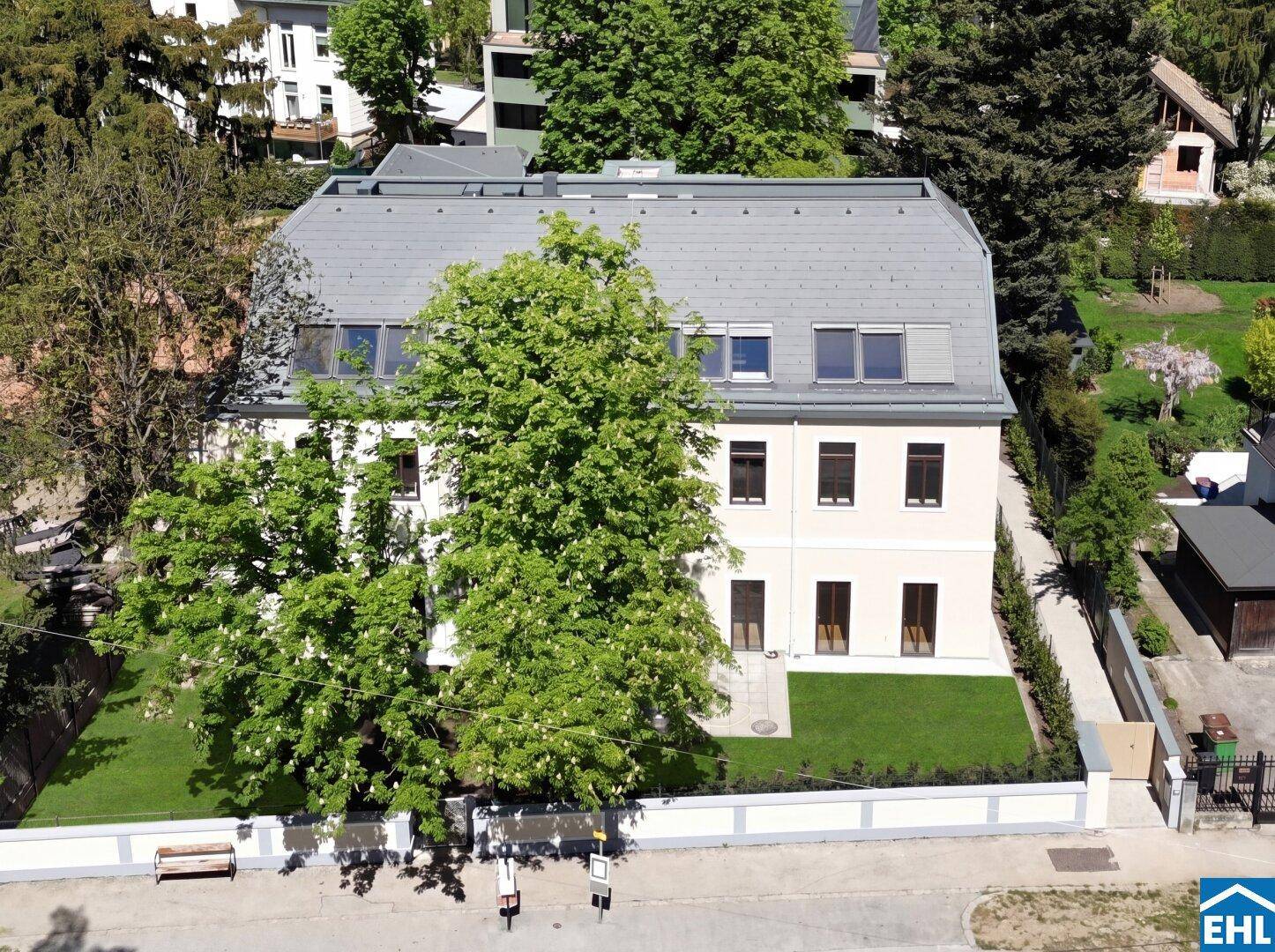 Ansicht des modernen Gebäudes von oben mit üppiger grüner Bepflanzung und gepflegtem Rasen.