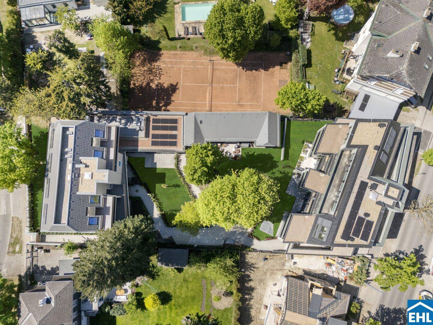 Luftaufnahme des gesamten Anwesens mit mehreren Gebäuden, Grünflächen, Tennisplatz und Pool.