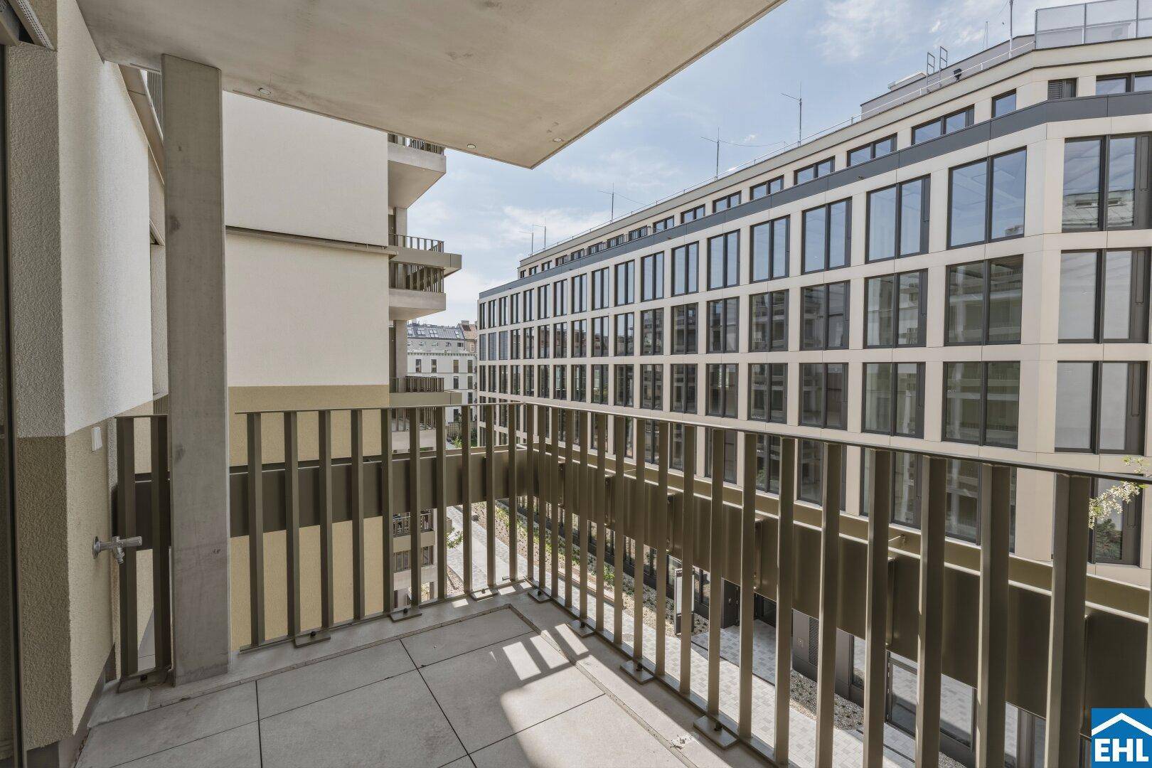 Geräumiger Balkon mit Fliesenboden und Aussicht auf die modernen Neubauten der Umgebung.