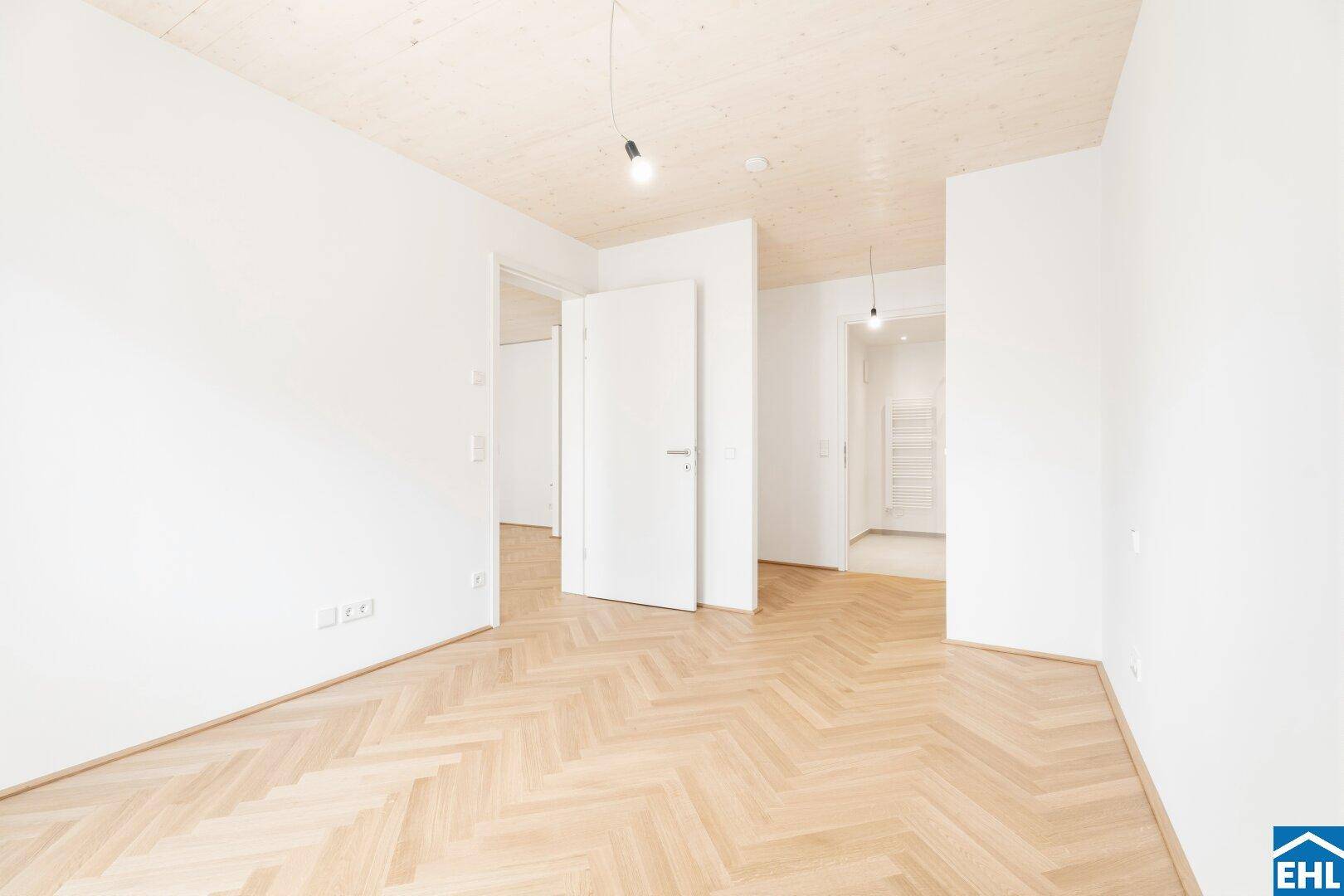 Geräumiges Schlafzimmer mit Fischgrätparkett und Holzbalkendecke, ideal für individuelle Gestaltung.