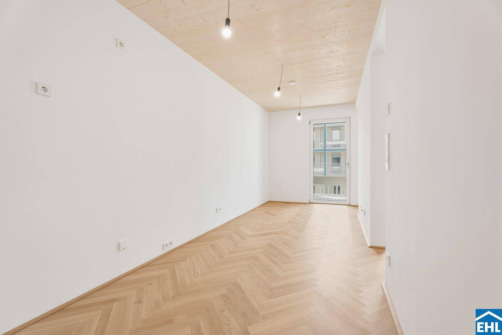 Geräumiges, helles Zimmer mit Fischgrätparkett, Holzbalkendecke und Zugang zum Balkon.