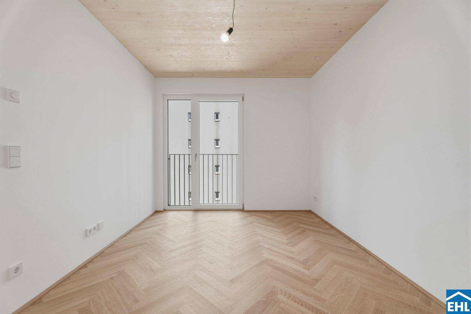 Helles Zimmer mit Fischgrätparkett und französischem Balkon, ideal für ein Schlafzimmer oder Büro.