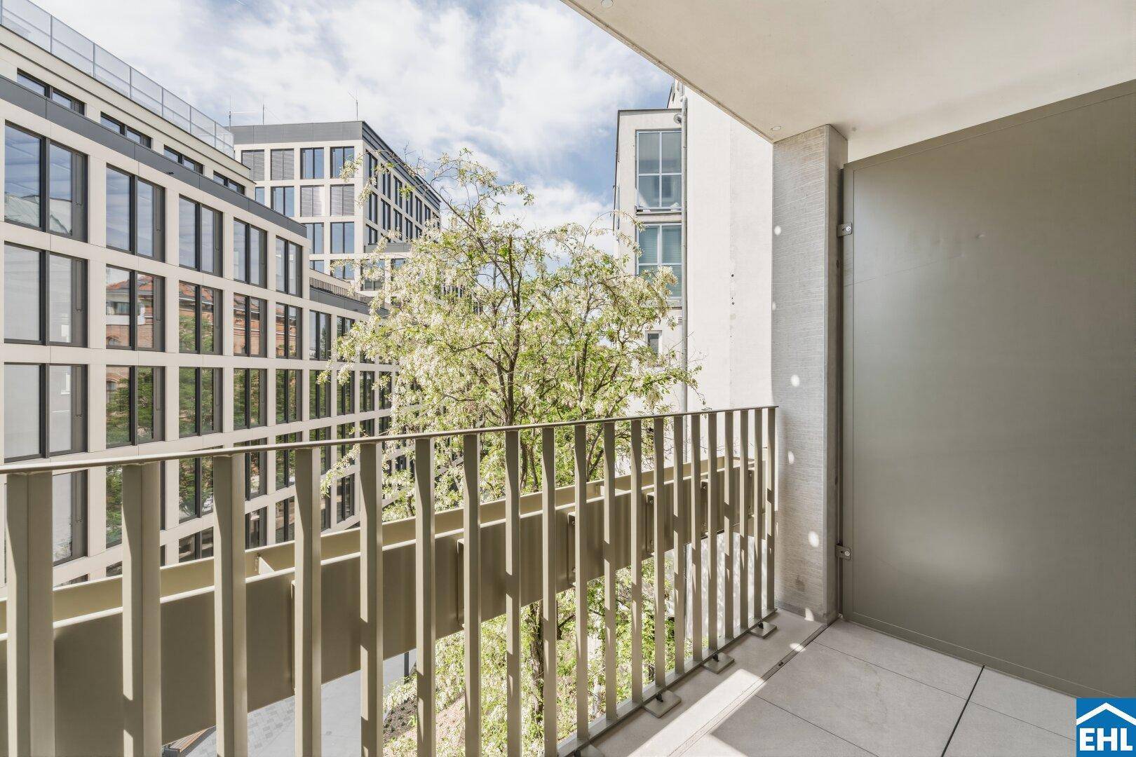 Balkon mit Blick ins Grüne und auf die umliegenden modernen Wohngebäude.
