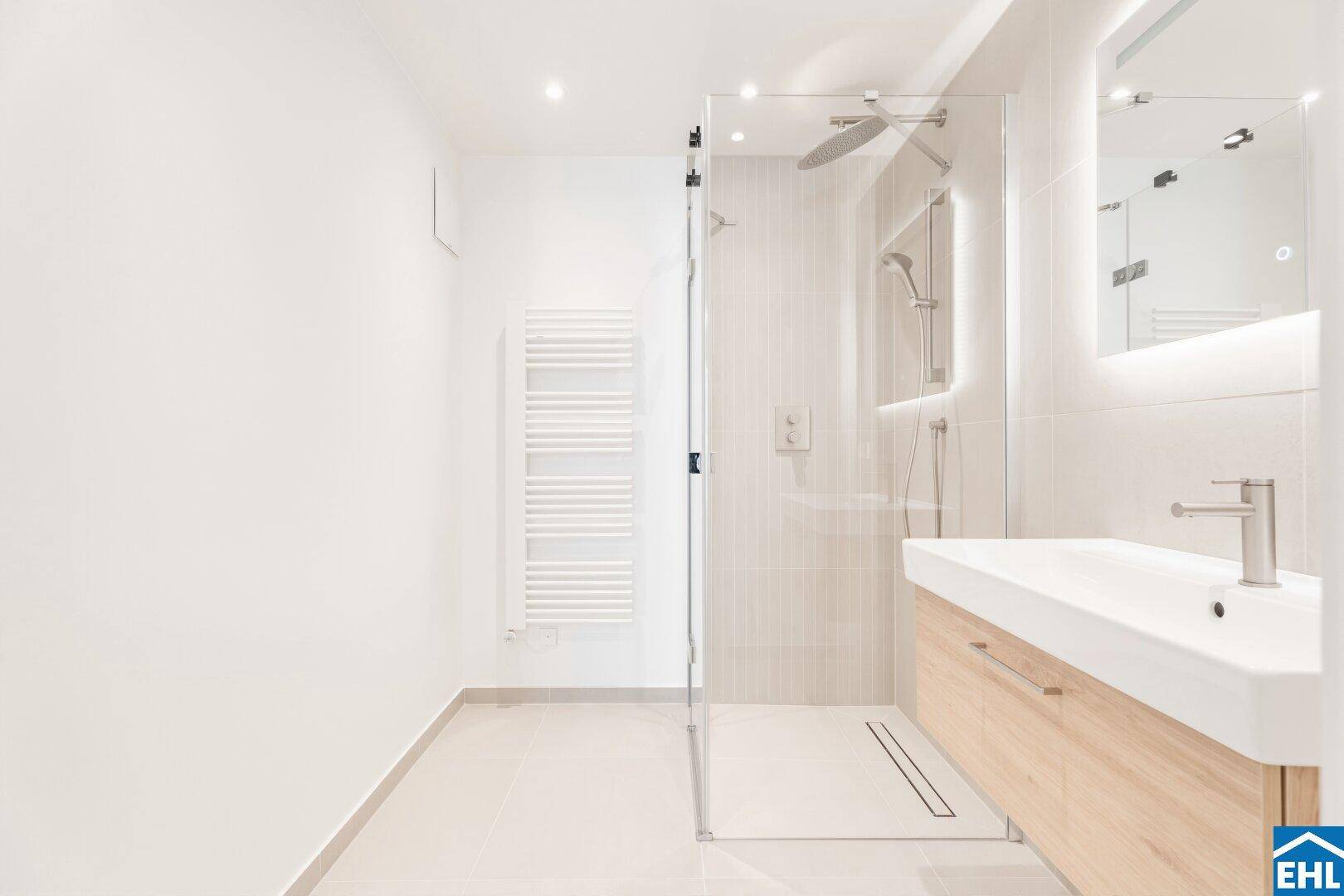 Modernes Badezimmer mit ebenerdiger Dusche, Holzwaschtisch und beheiztem Handtuchhalter.