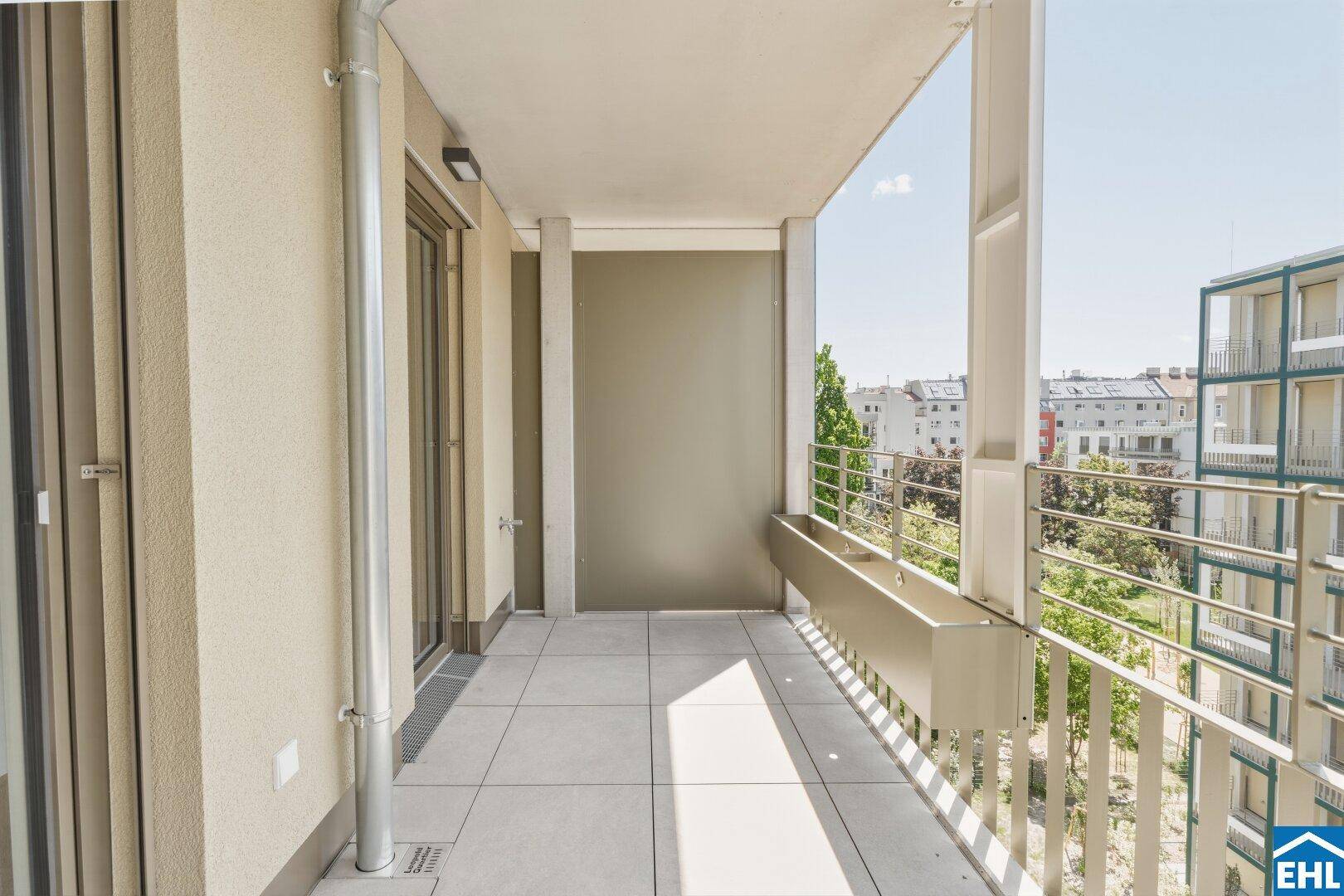 Geräumiger Balkon mit Fliesenboden und Metallgeländer, bietet einen Blick auf die umliegenden Gebäude.