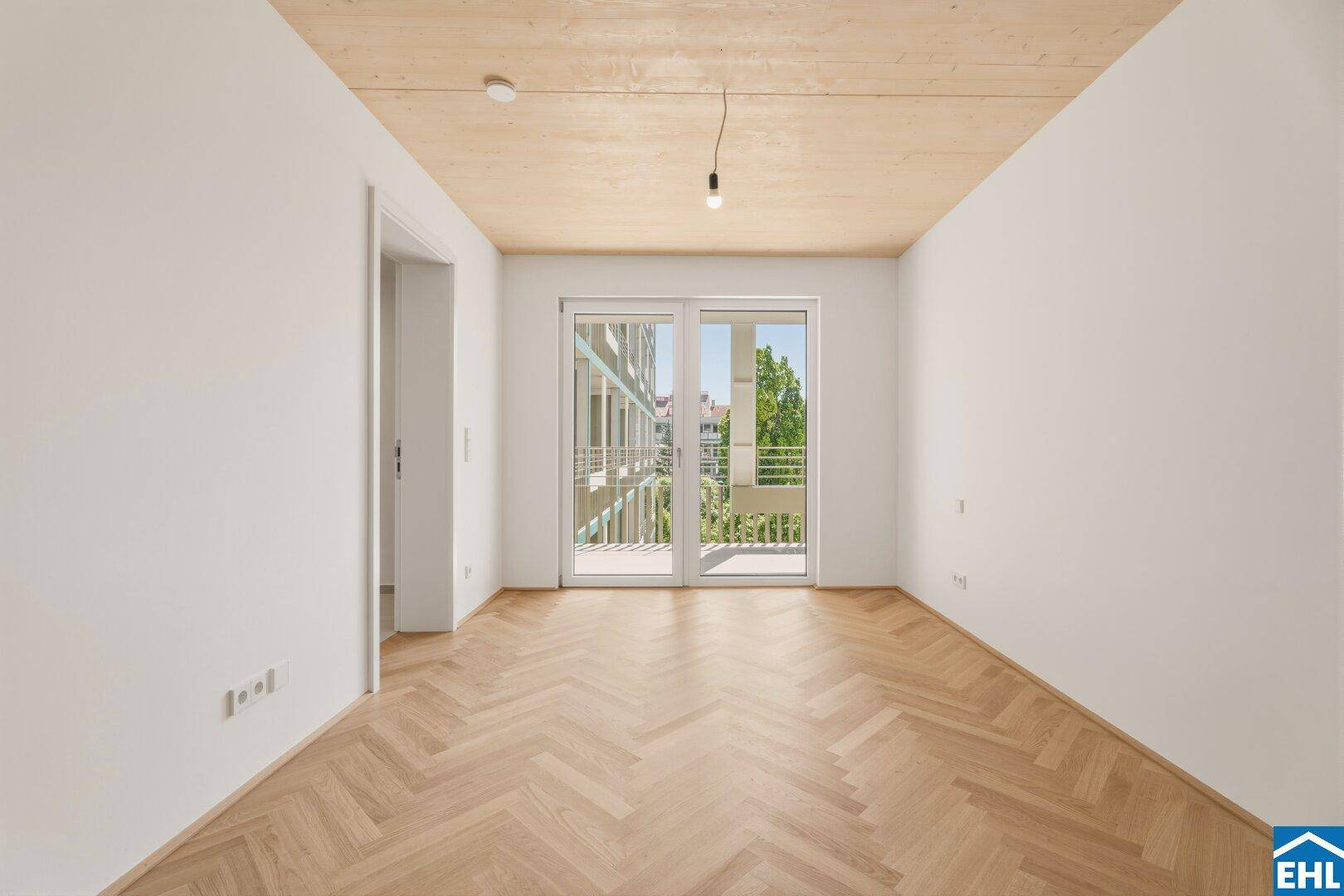 Helles Schlafzimmer mit Fischgrätparkett und Zugang zu einem französischen Balkon.