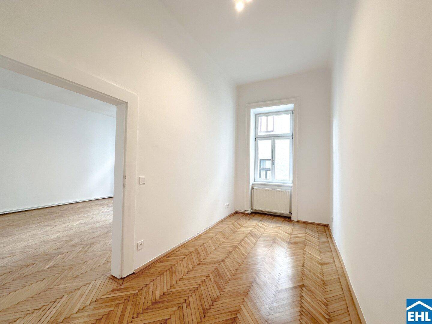 Gemütliches Zimmer mit Fischgrätparkett, hellen Wänden und einem Fenster.