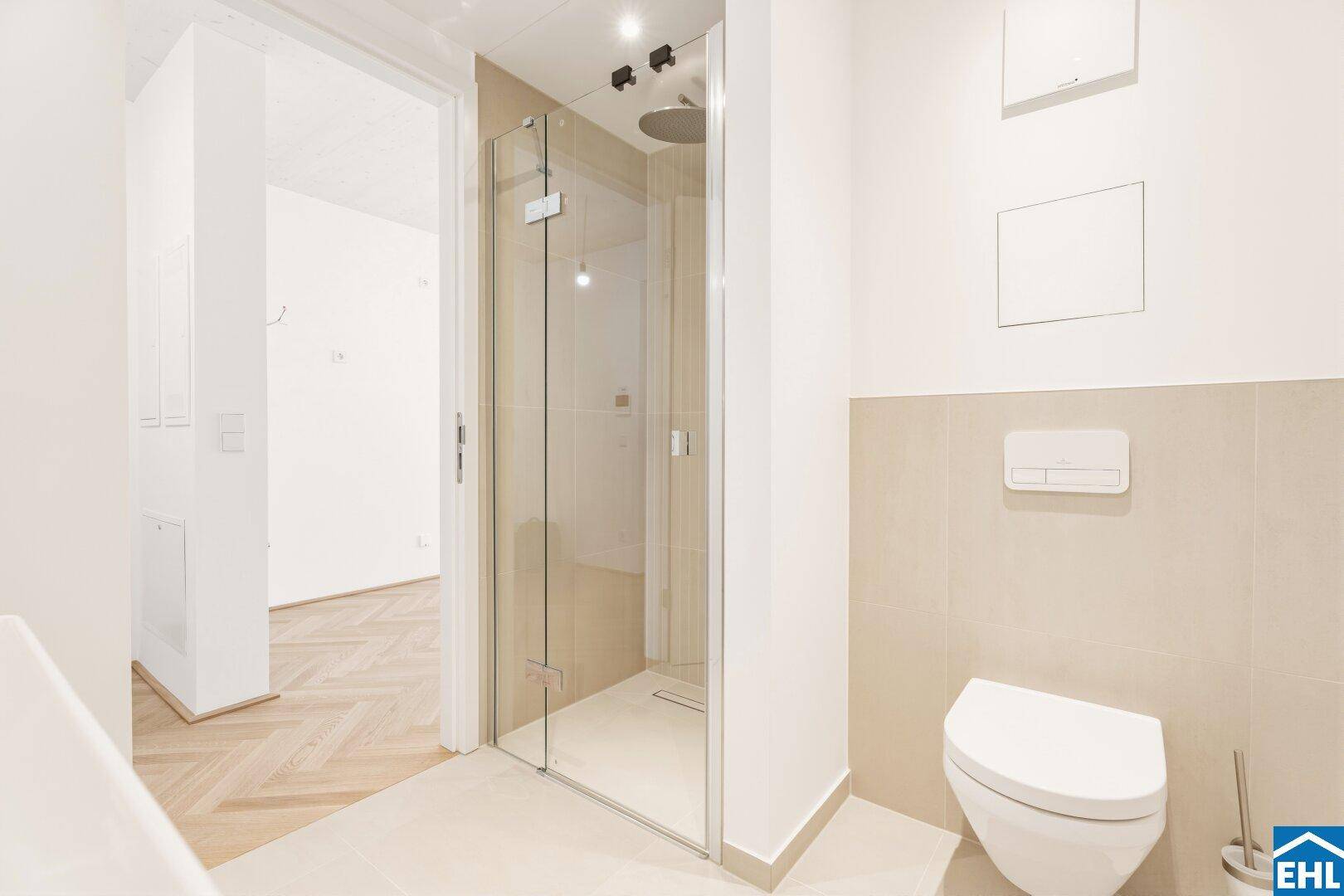 Zeitgemäßes Badezimmer mit großer Glasdusche und Wand-WC, verbunden mit einem hellen Flur.