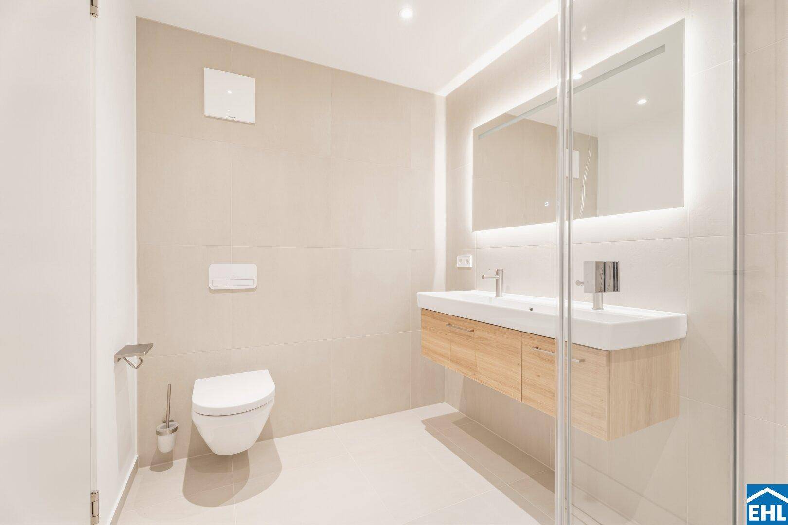 Helles Badezimmer mit wandhängendem WC, modernem Waschtisch und großer Dusche.