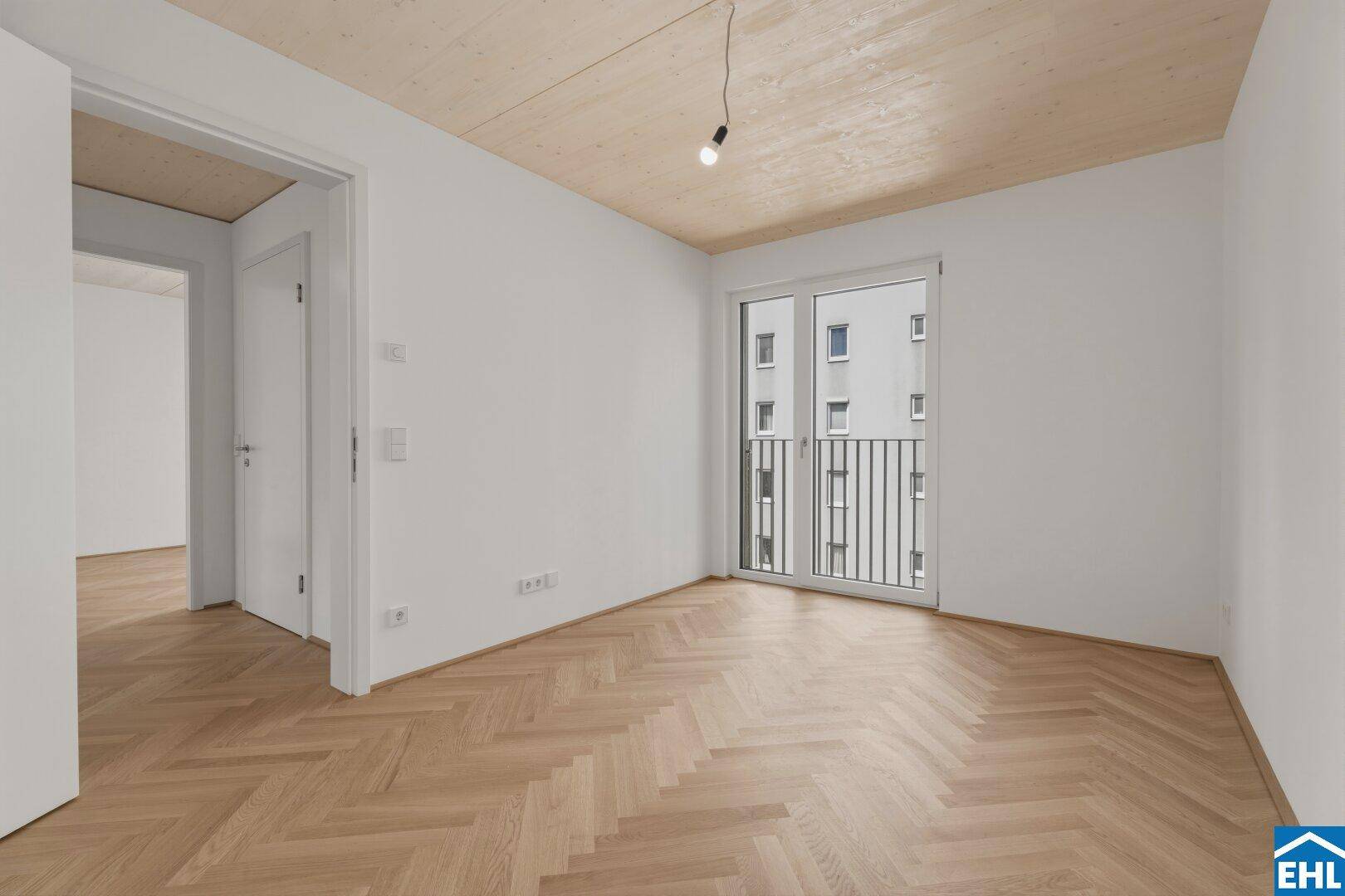 Geräumiges Schlafzimmer mit Fischgrätparkett, Holzbalkendecke und Zugang zu einem französischen Balkon.