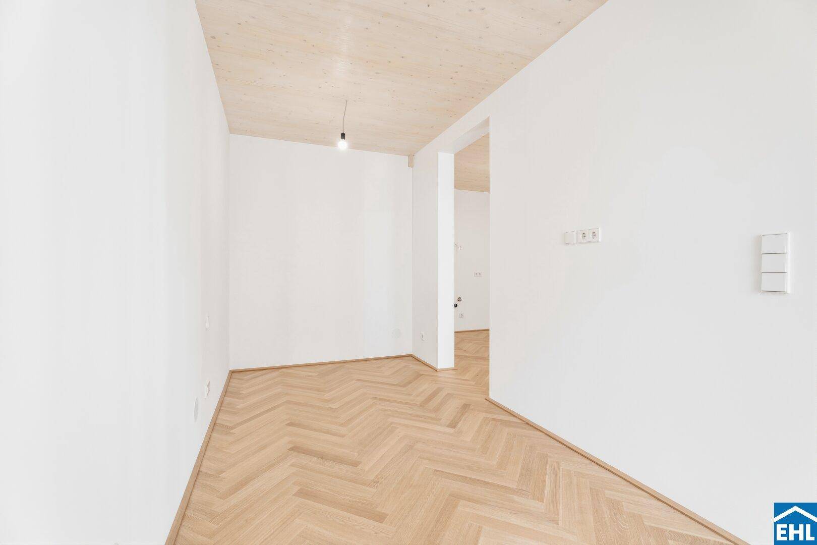 Unmöblierter Raum mit Fischgrätparkett und weißen Wänden, bereit für neue Bewohner und individuelle Gestaltung.
