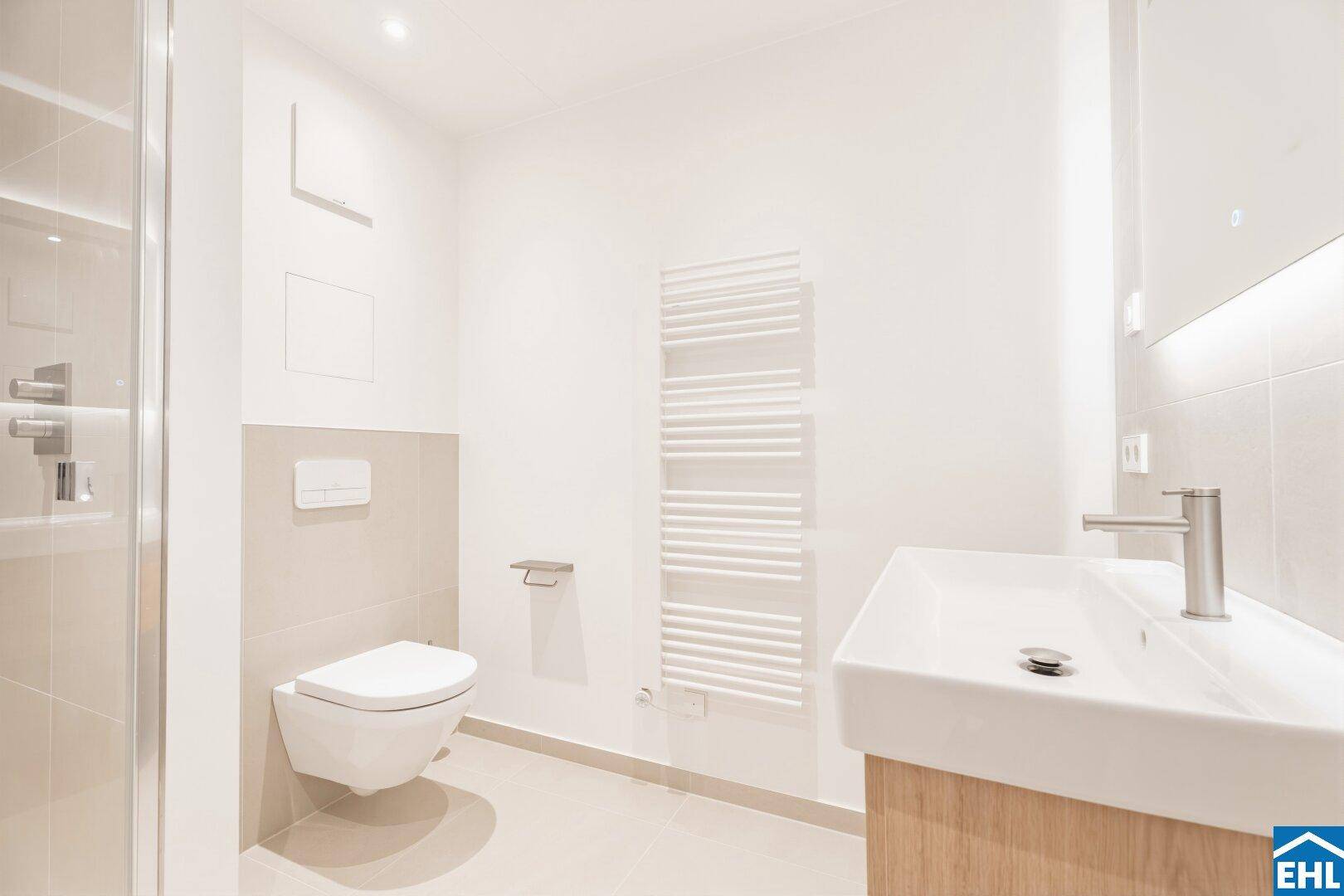 Modernes Badezimmer mit wandhängendem WC, Waschtisch und beheiztem Handtuchhalter, in hellen Tönen gehalten.