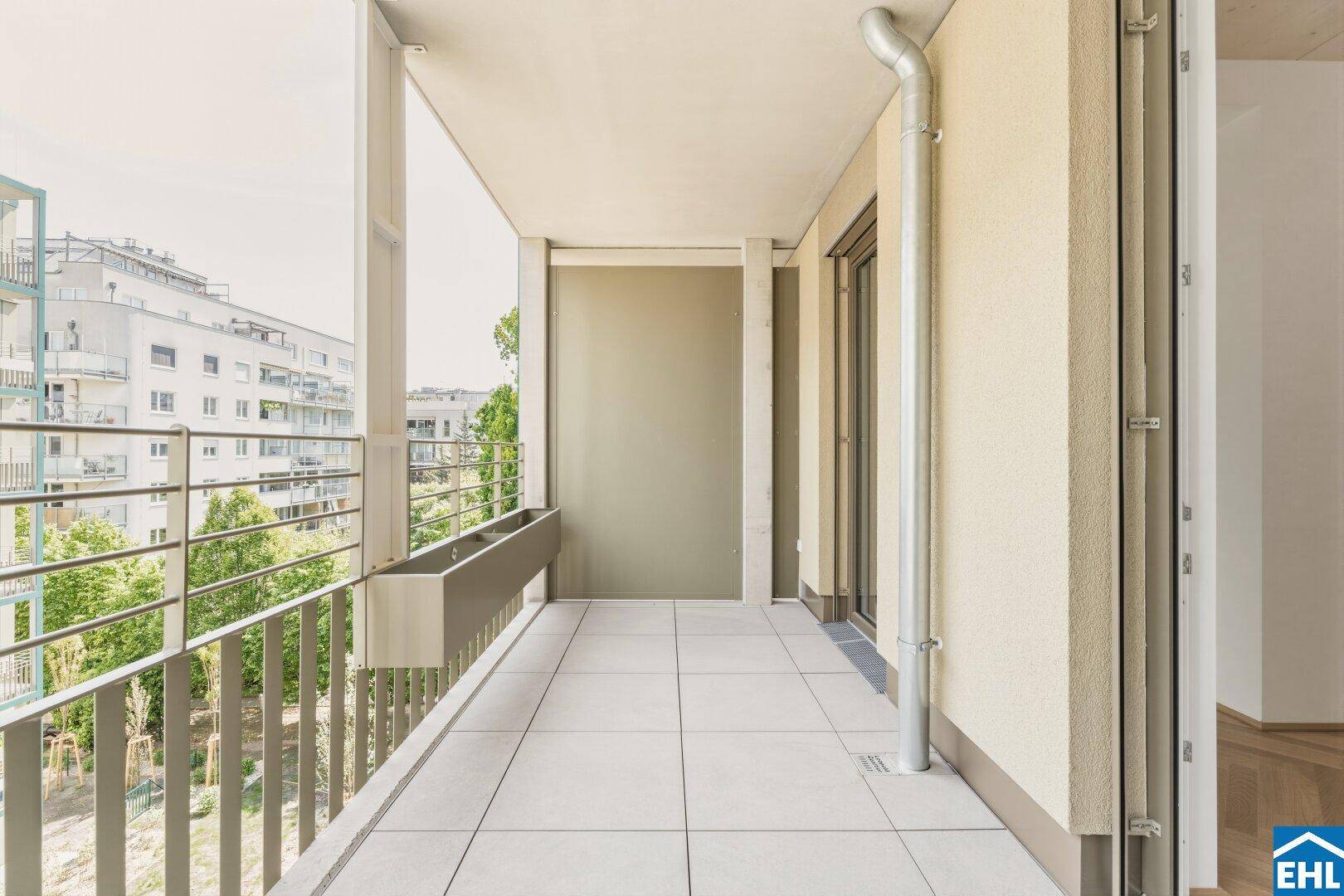 Geräumiger Balkon mit Fliesenboden und Blick auf die umliegende Wohnbebauung, ideal zum Entspannen.