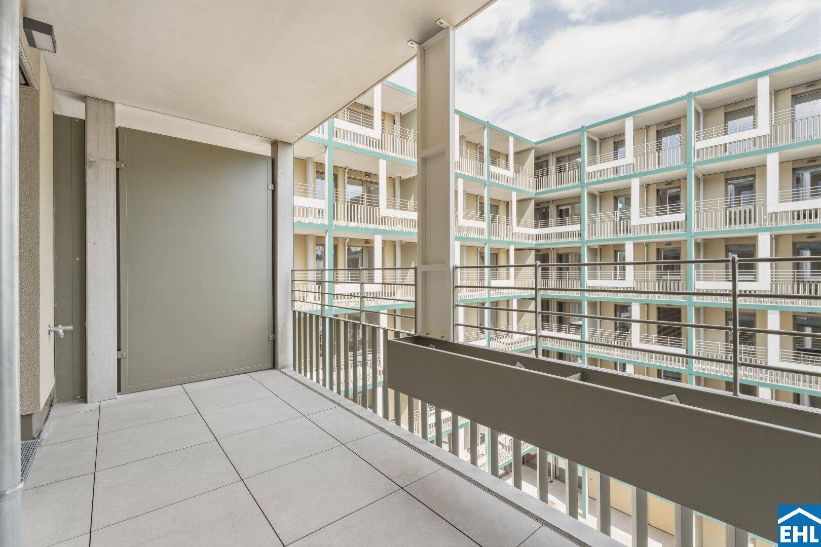 Balkon mit Blick auf den begrünten Innenhof und die moderne Architektur des Gebäudes, sehr ansprechend.