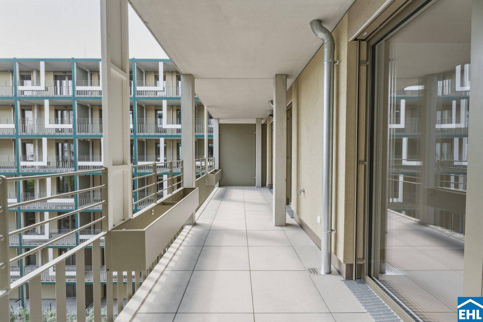 Geräumiger Balkon mit Fliesenboden und Blick auf die umliegenden Gebäude.