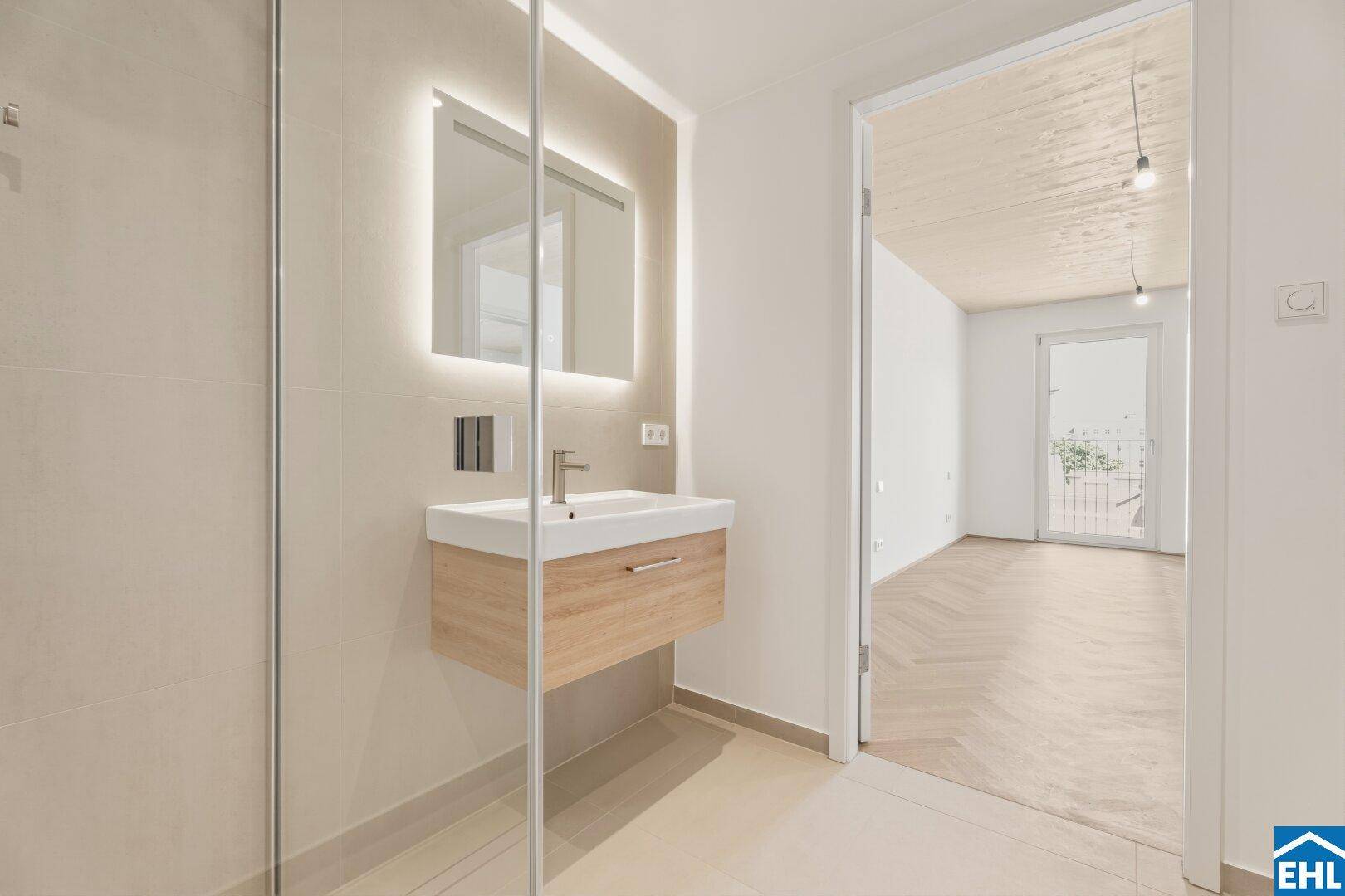 Elegantes Badezimmer mit begehbarer Dusche, Einzelwaschbecken und Blick in den Wohnbereich.